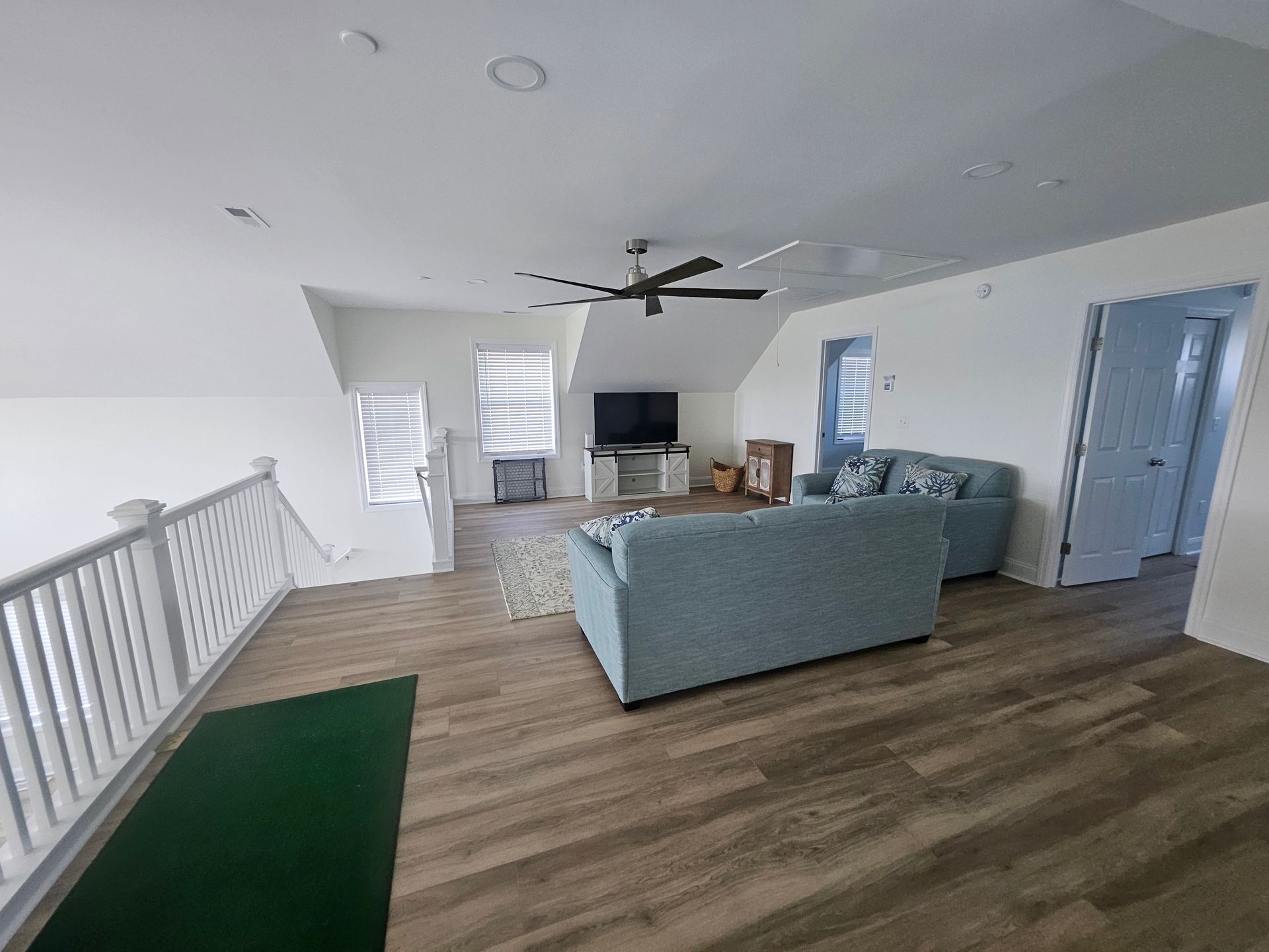A living room with a couch, television, and ceiling fan.