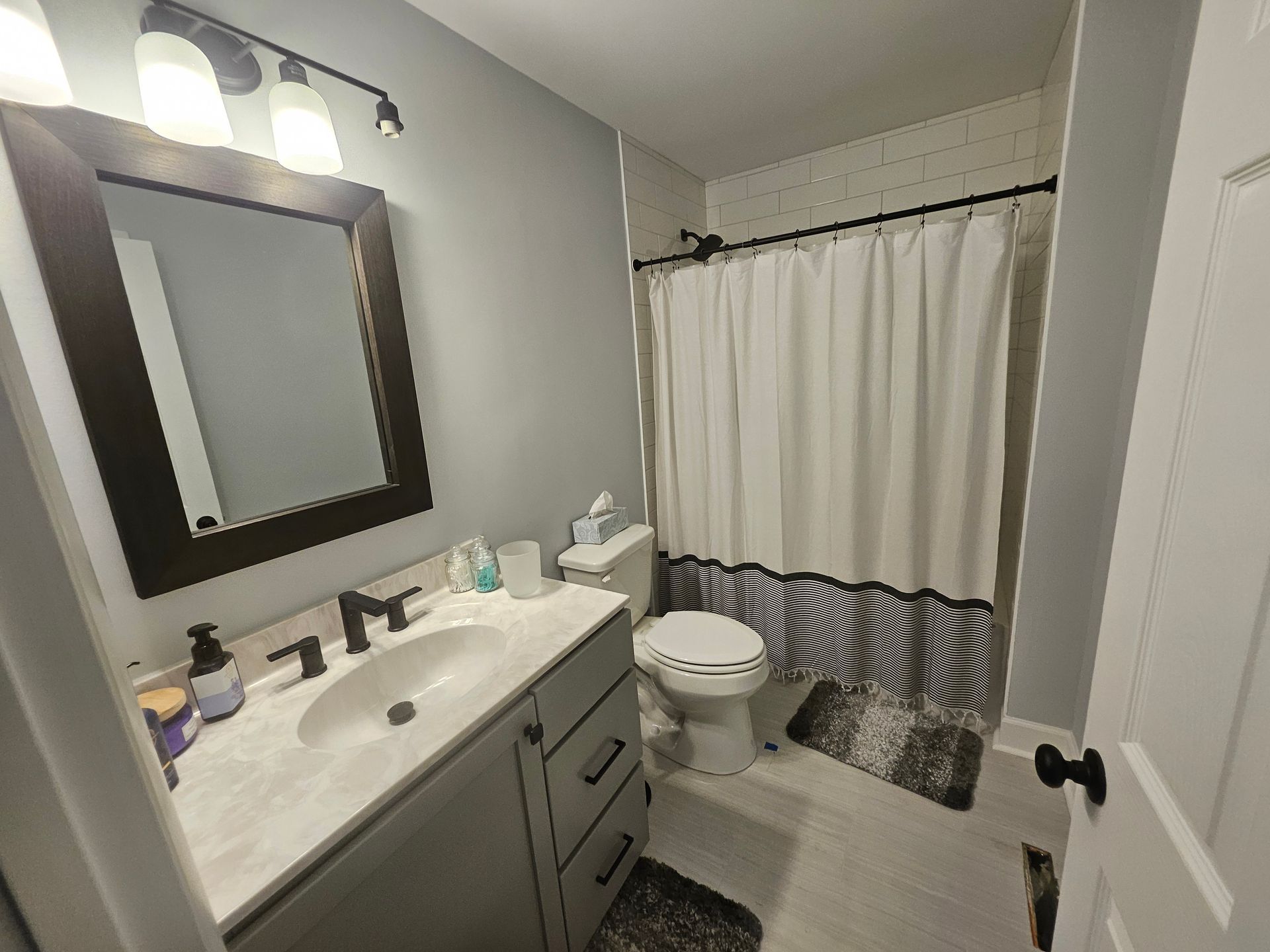 A bathroom with a sink, toilet, mirror, and shower curtain