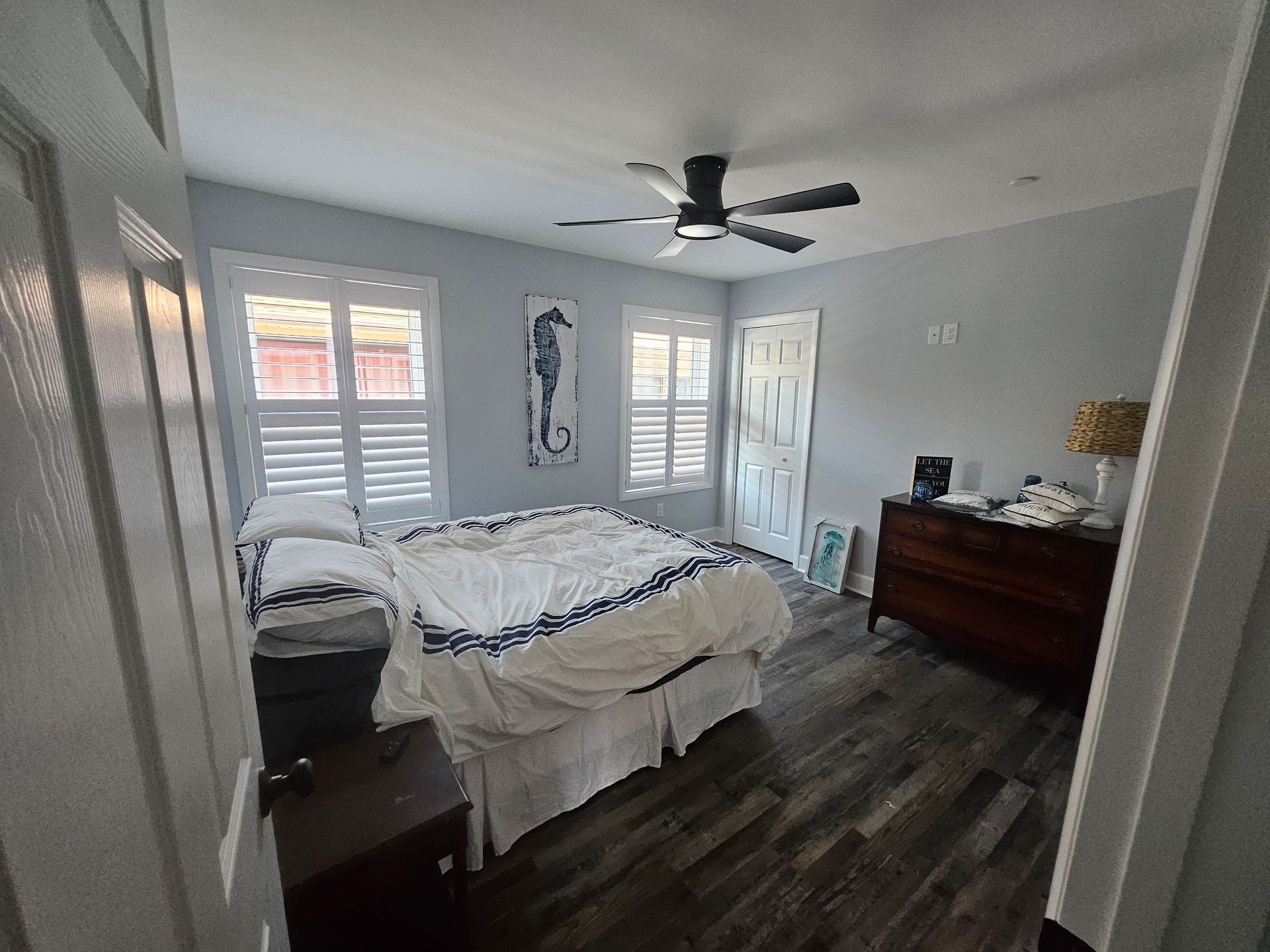 A bedroom with a bed, dresser, nightstand and ceiling fan