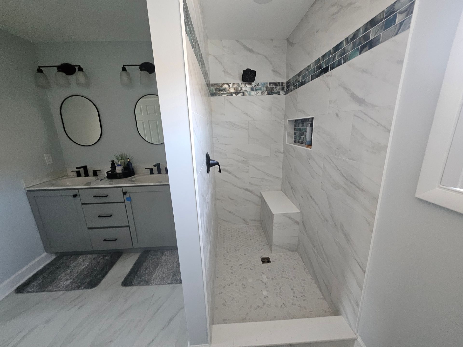 A bathroom with a walk in shower and a sink