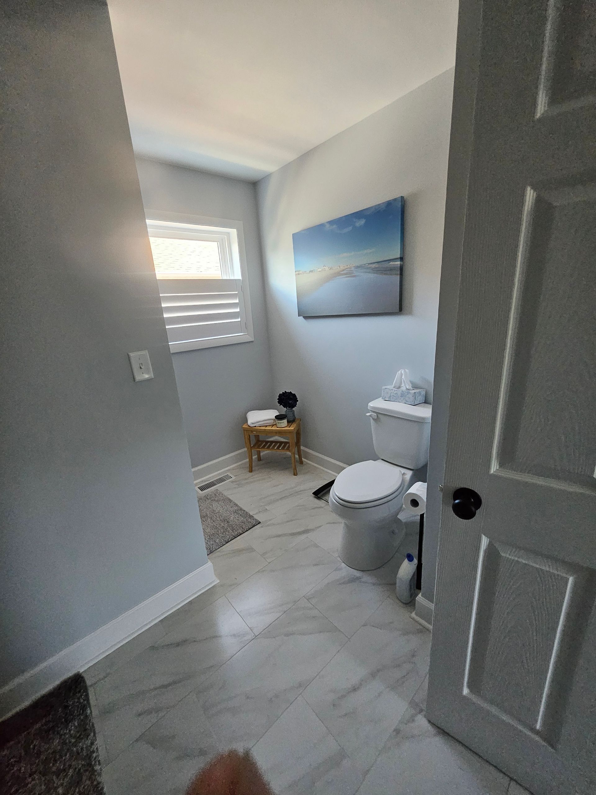 A bathroom with a toilet and a painting on the wall