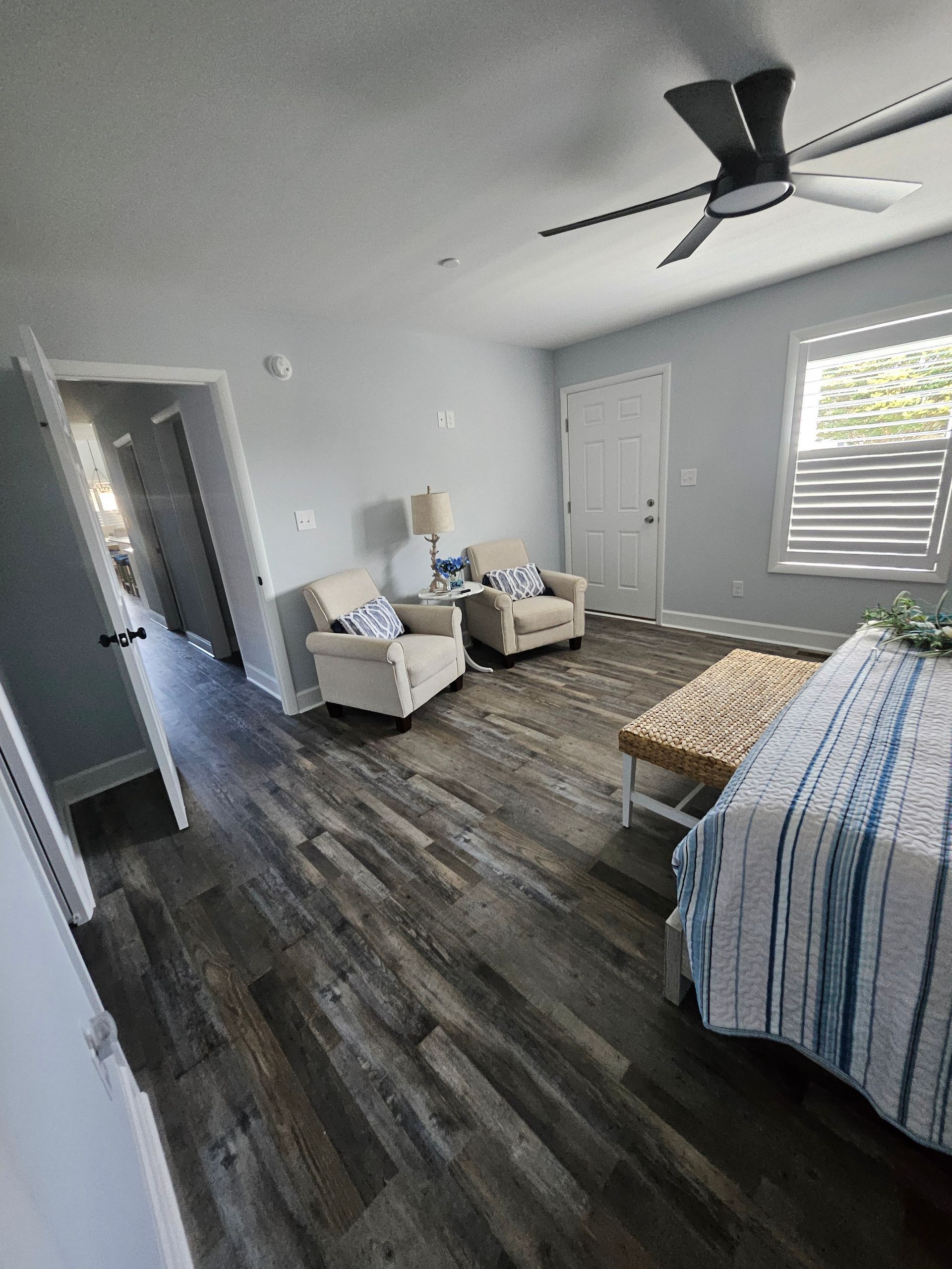 A bedroom with a bed, chairs, and a ceiling fan