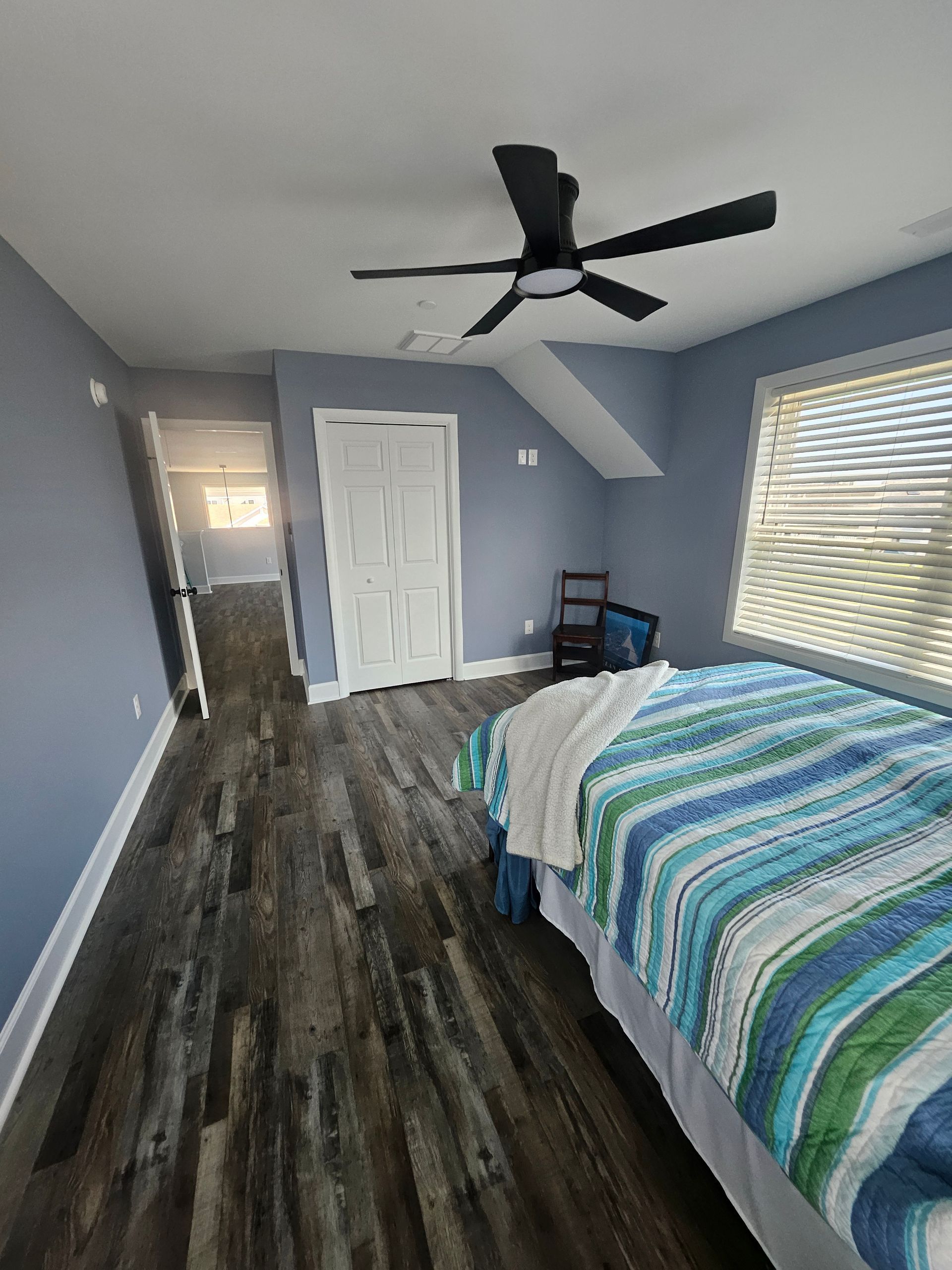 A bedroom with two beds and a ceiling fan
