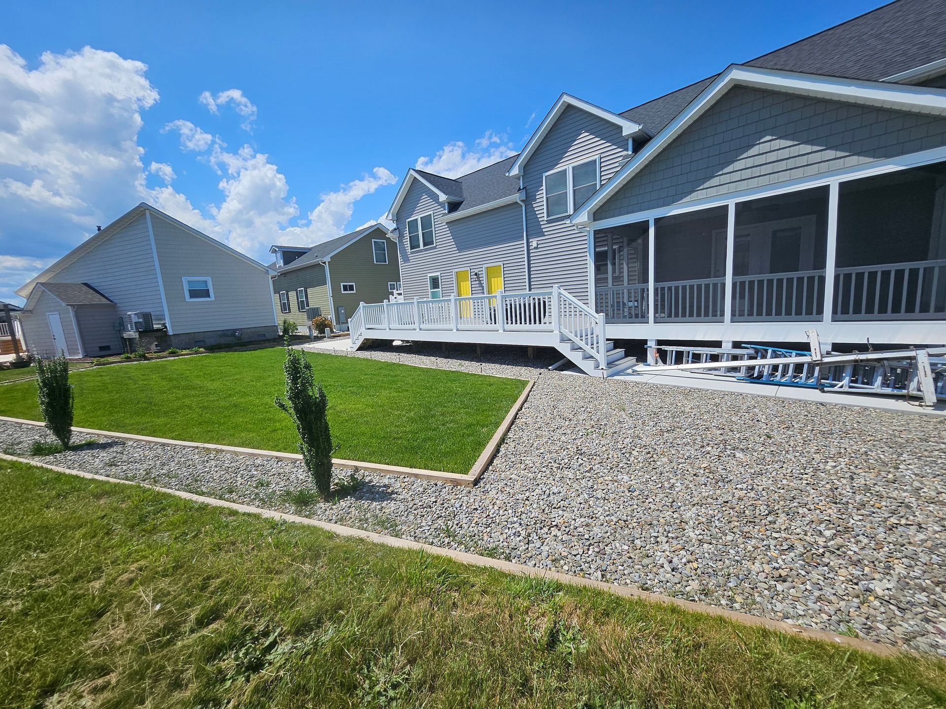 A house with a screened in porch and a large lawn in front of it