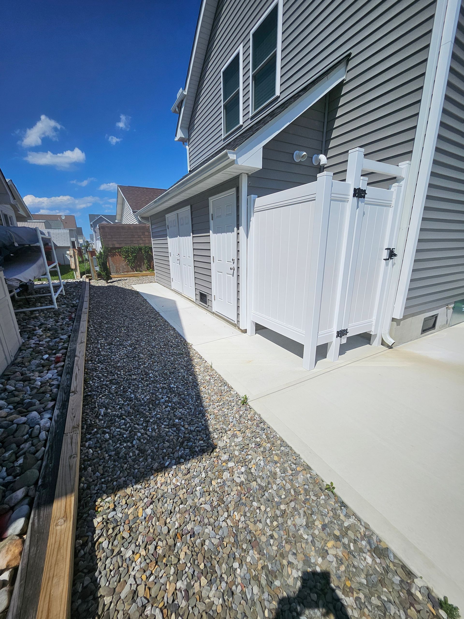 A house with a white fence and gravel in front of it
