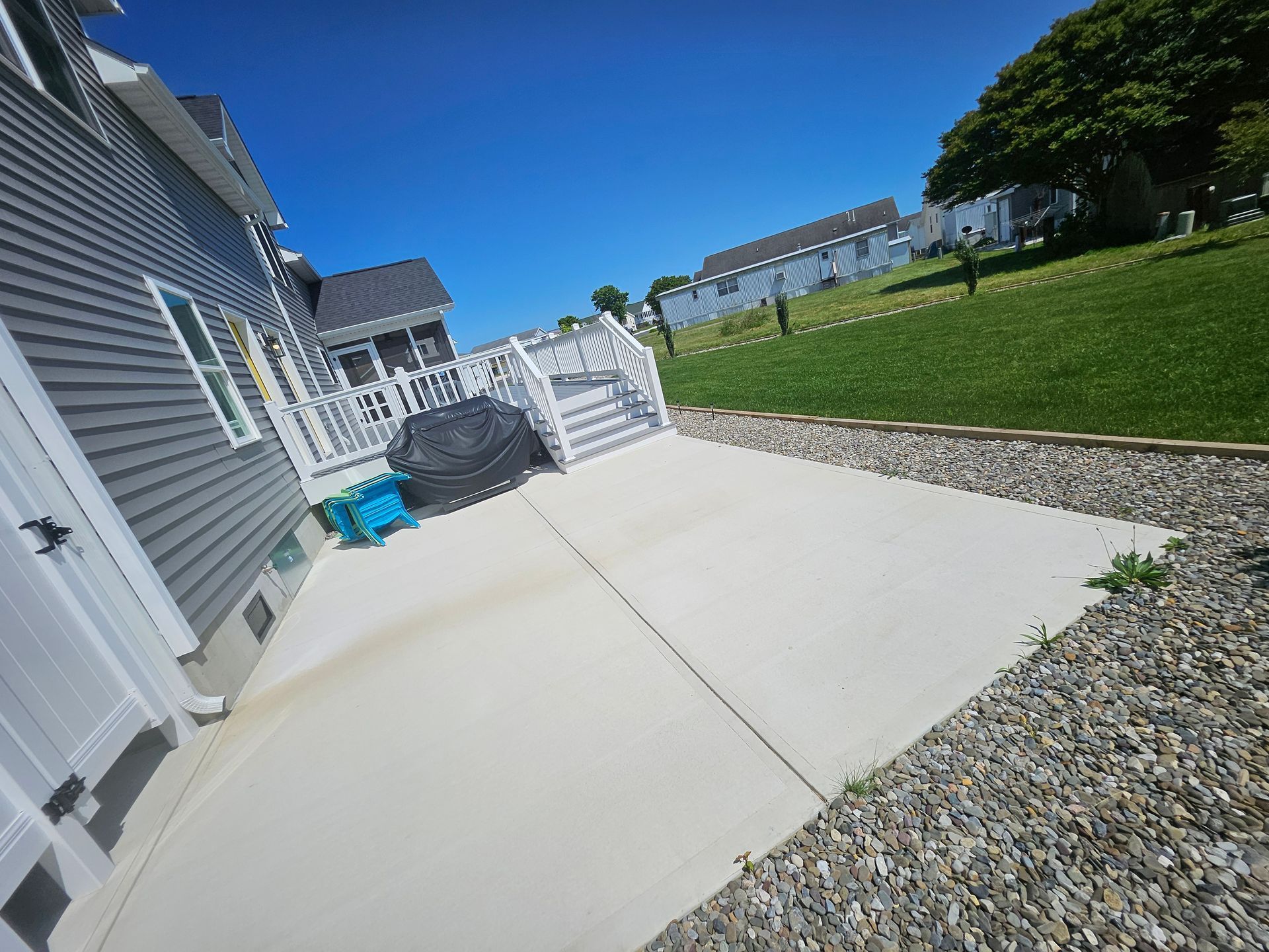 A concrete walkway leading to a house with a deck