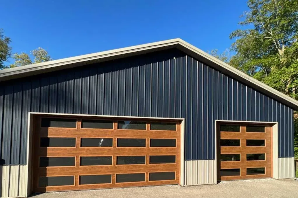 Dark blue metal-sided garage with two brown doors, set against a blue sky.