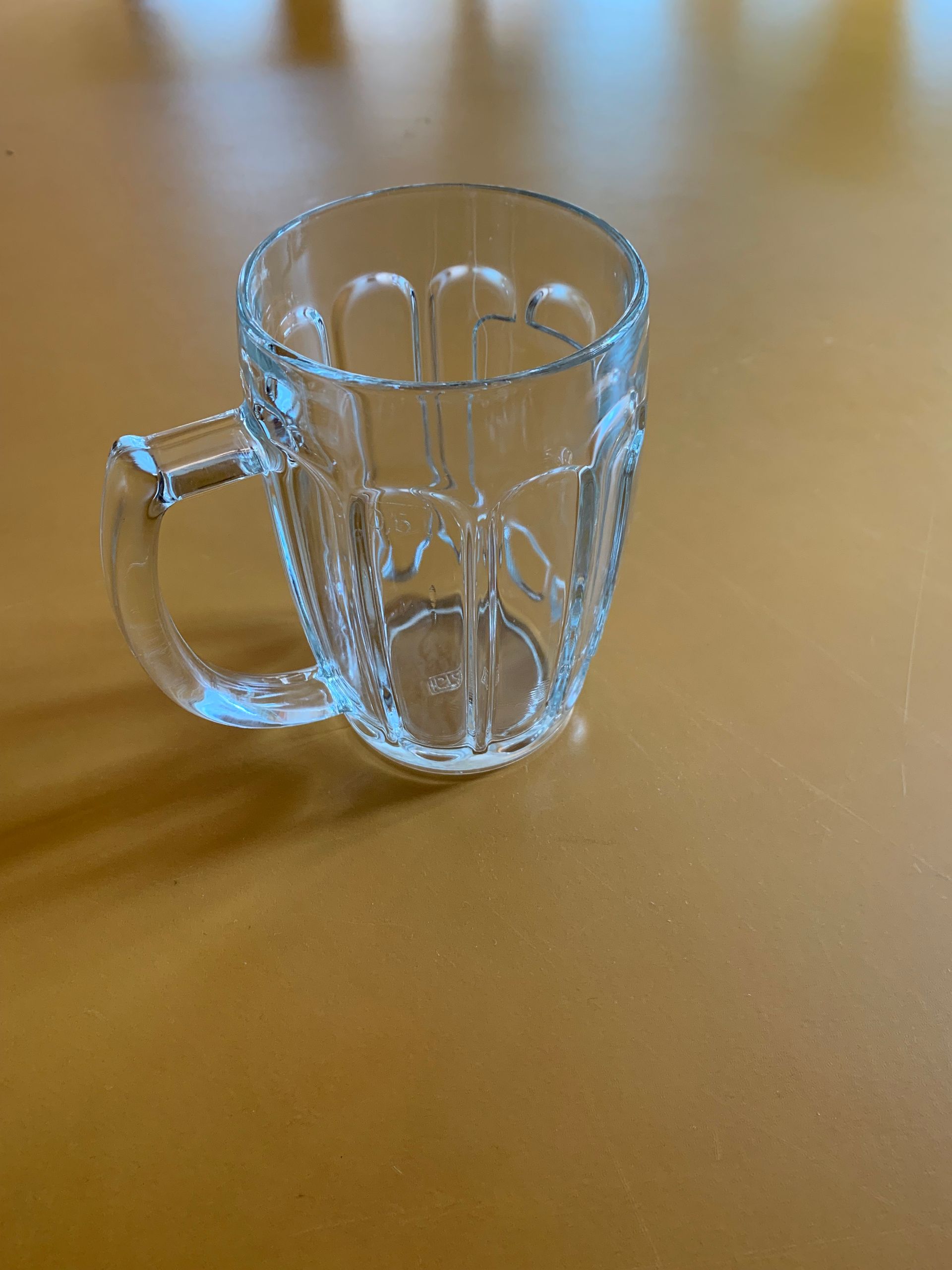 A clear glass mug with a handle is sitting on a table