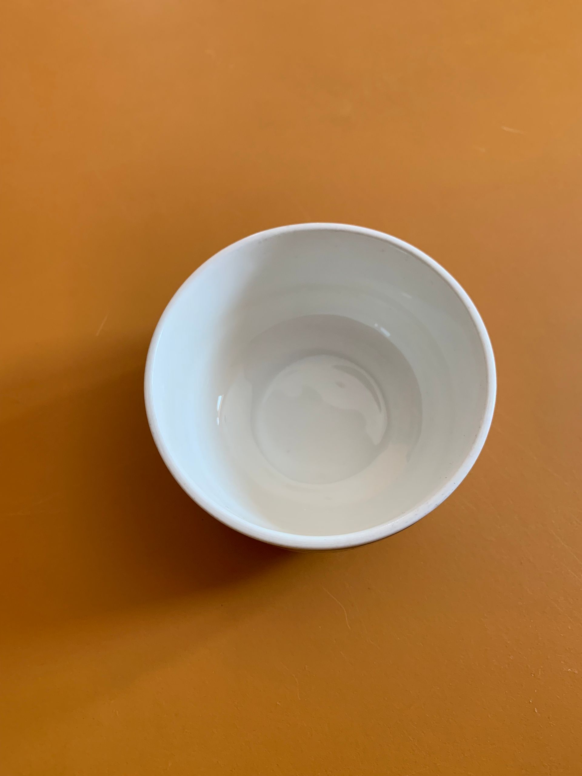 A white bowl is sitting on a brown table