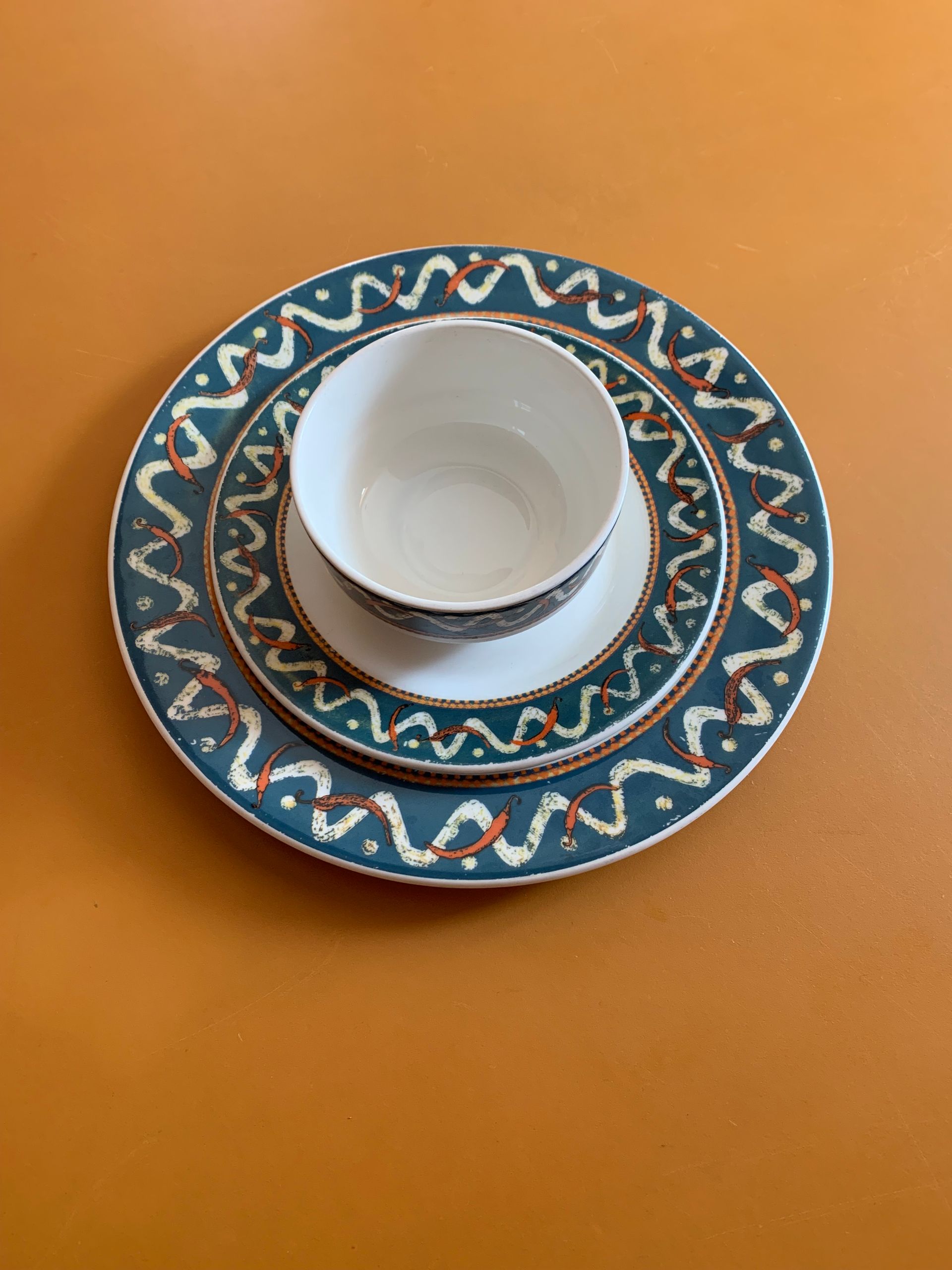 A set of three plates and a bowl on a table