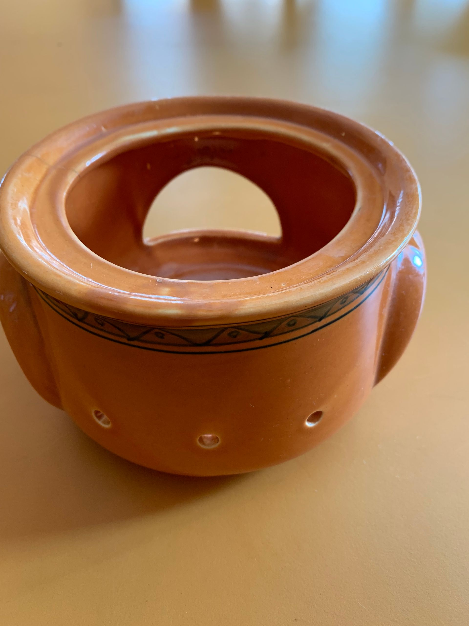 A brown bowl with holes in it is sitting on a table