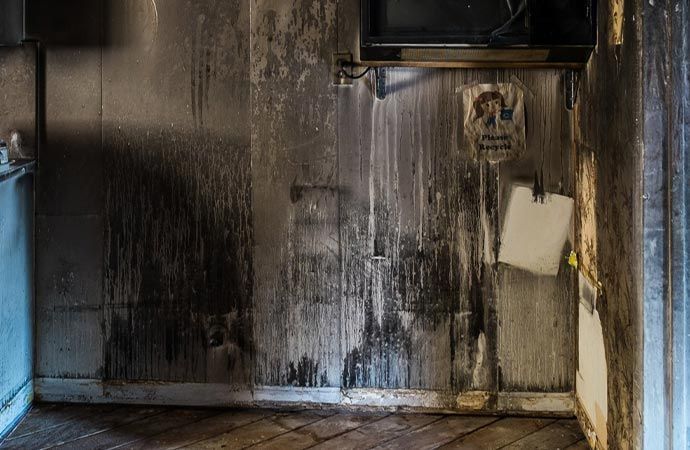 Interior view of a room damaged by fire; walls blackened with soot, debris.