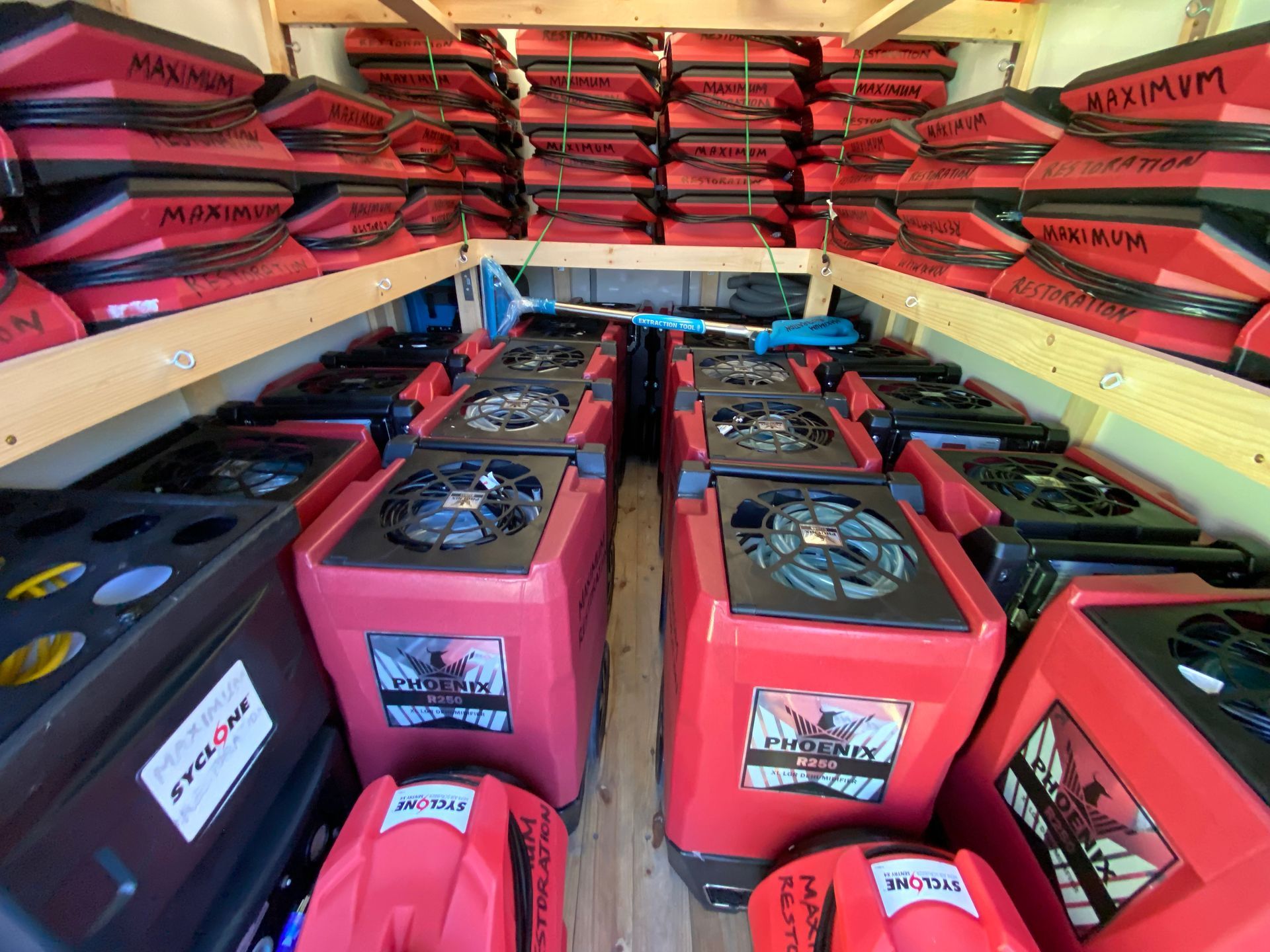 Inside a trailer: rows of red and black industrial dehumidifiers and stacked storage boxes.