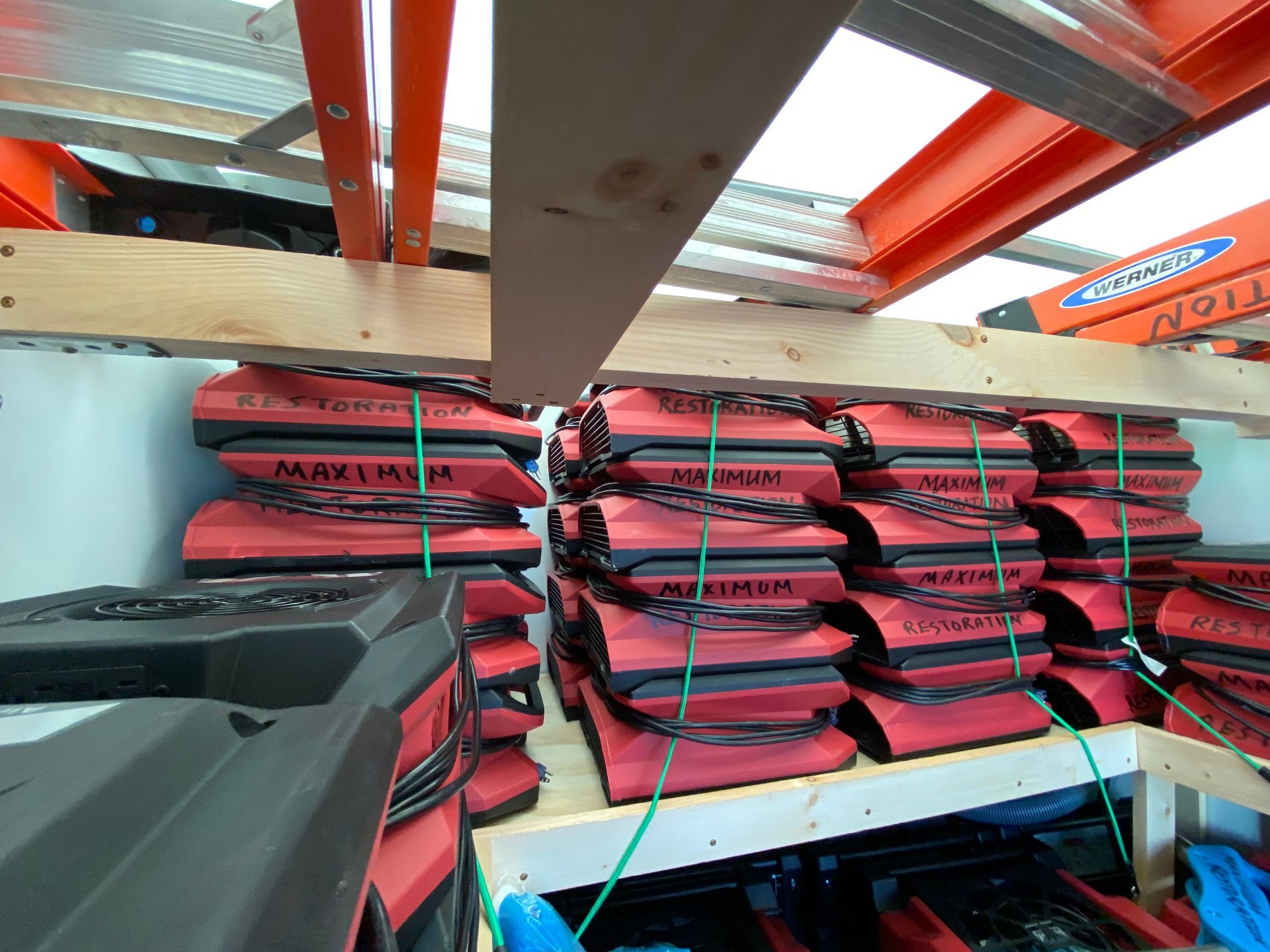 Stacks of red and black safety flotation devices on shelves, with ladders in the background.