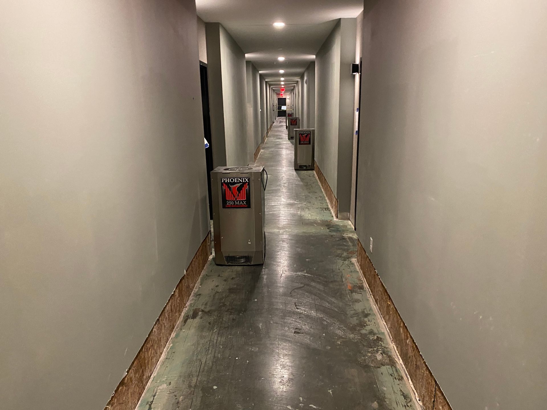 Long, narrow hallway with gray walls and a water heater in the center.