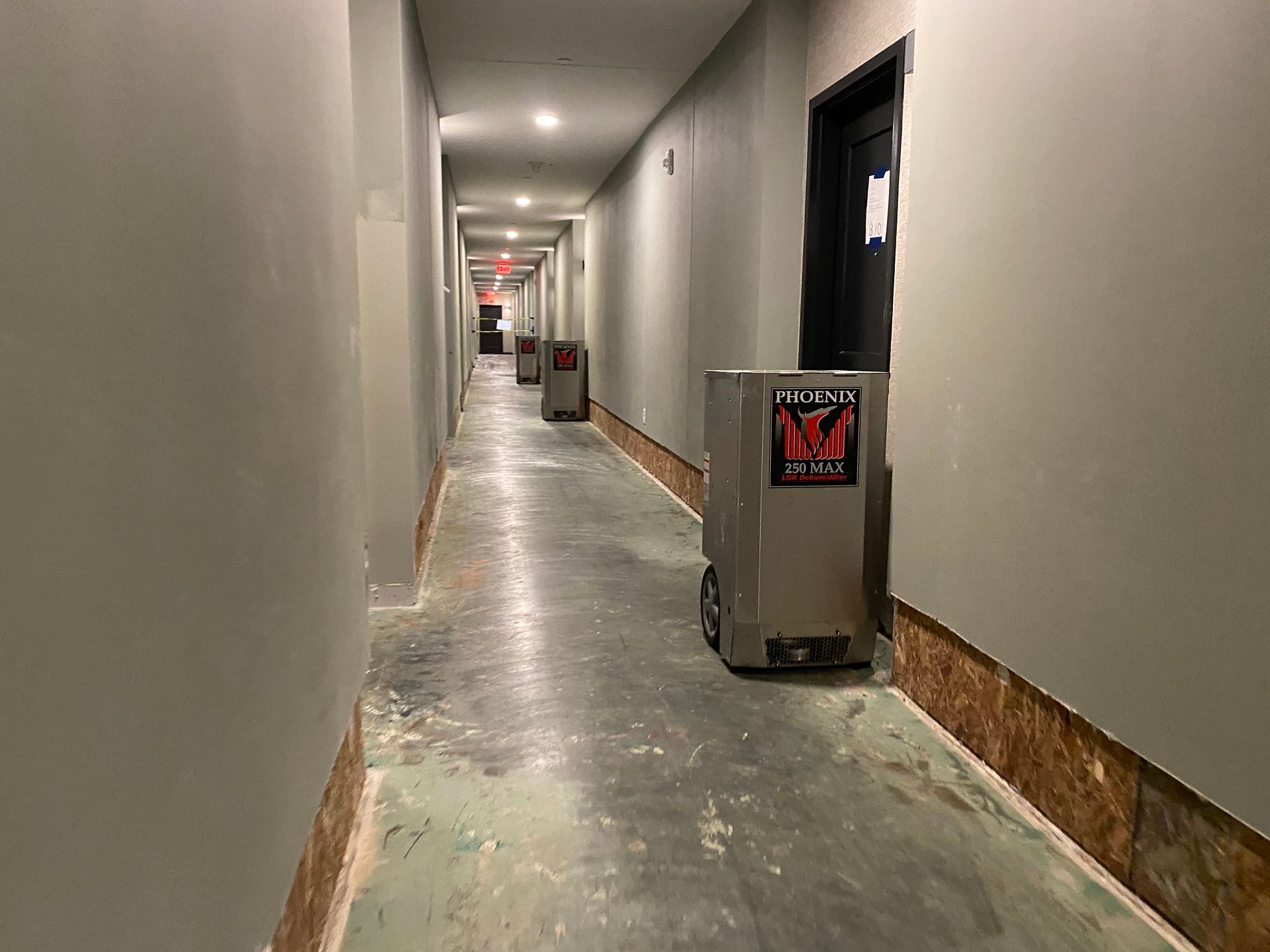 Hallway with gray walls, robots, and a dark door.