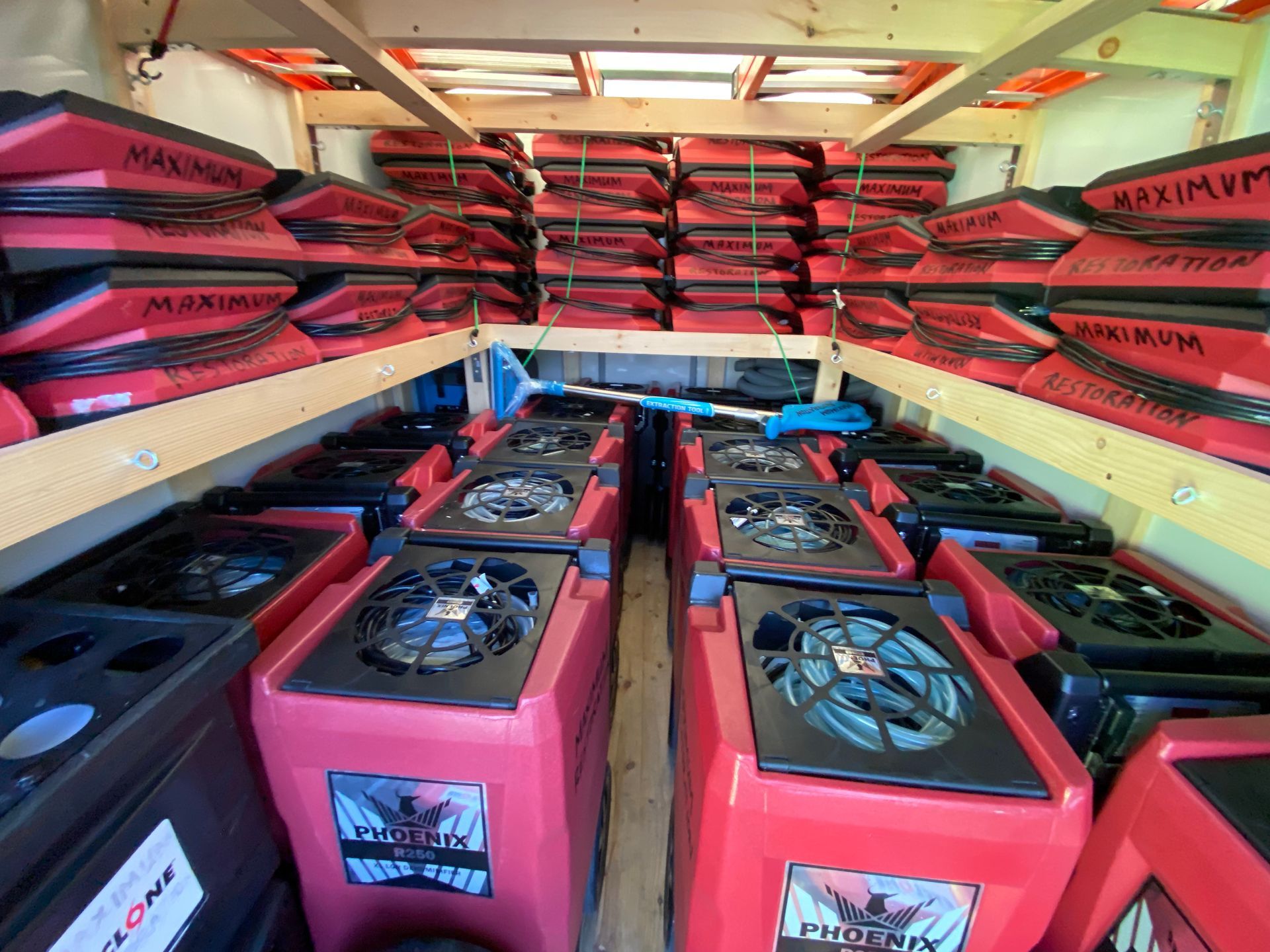 Inside a truck, rows of red industrial air movers and stacked red boxes labeled 