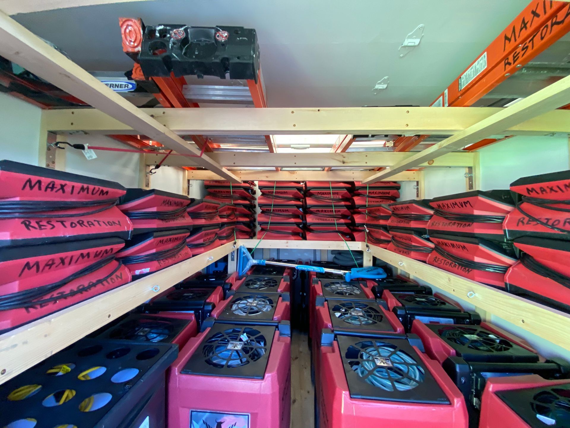 Interior of a storage trailer filled with stacks of red and black equipment, likely HVAC systems, on shelves.