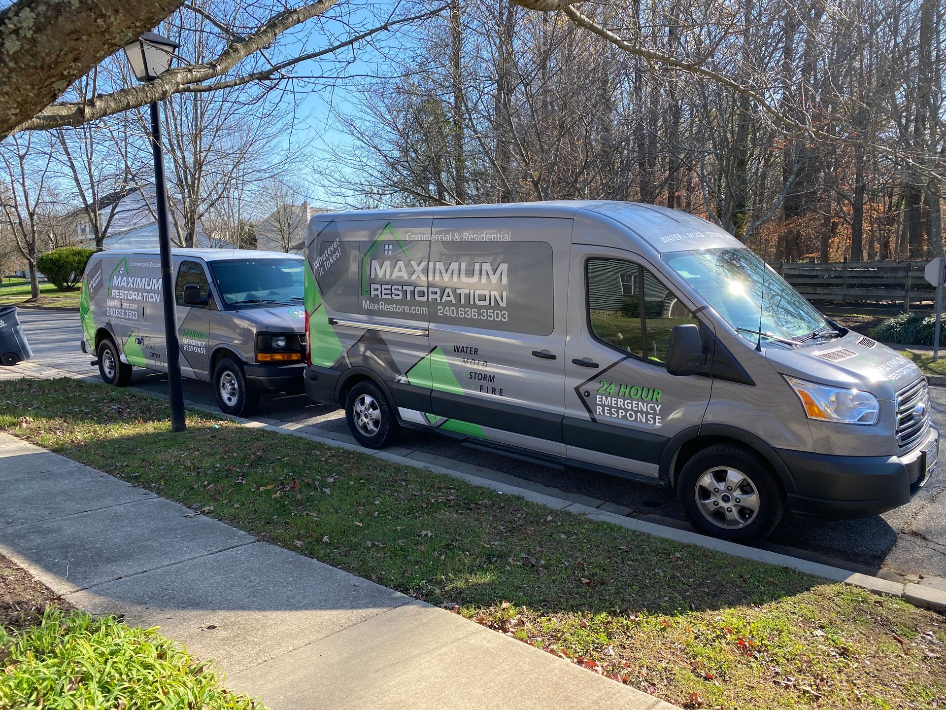 Two grey vans parked, with company logo 