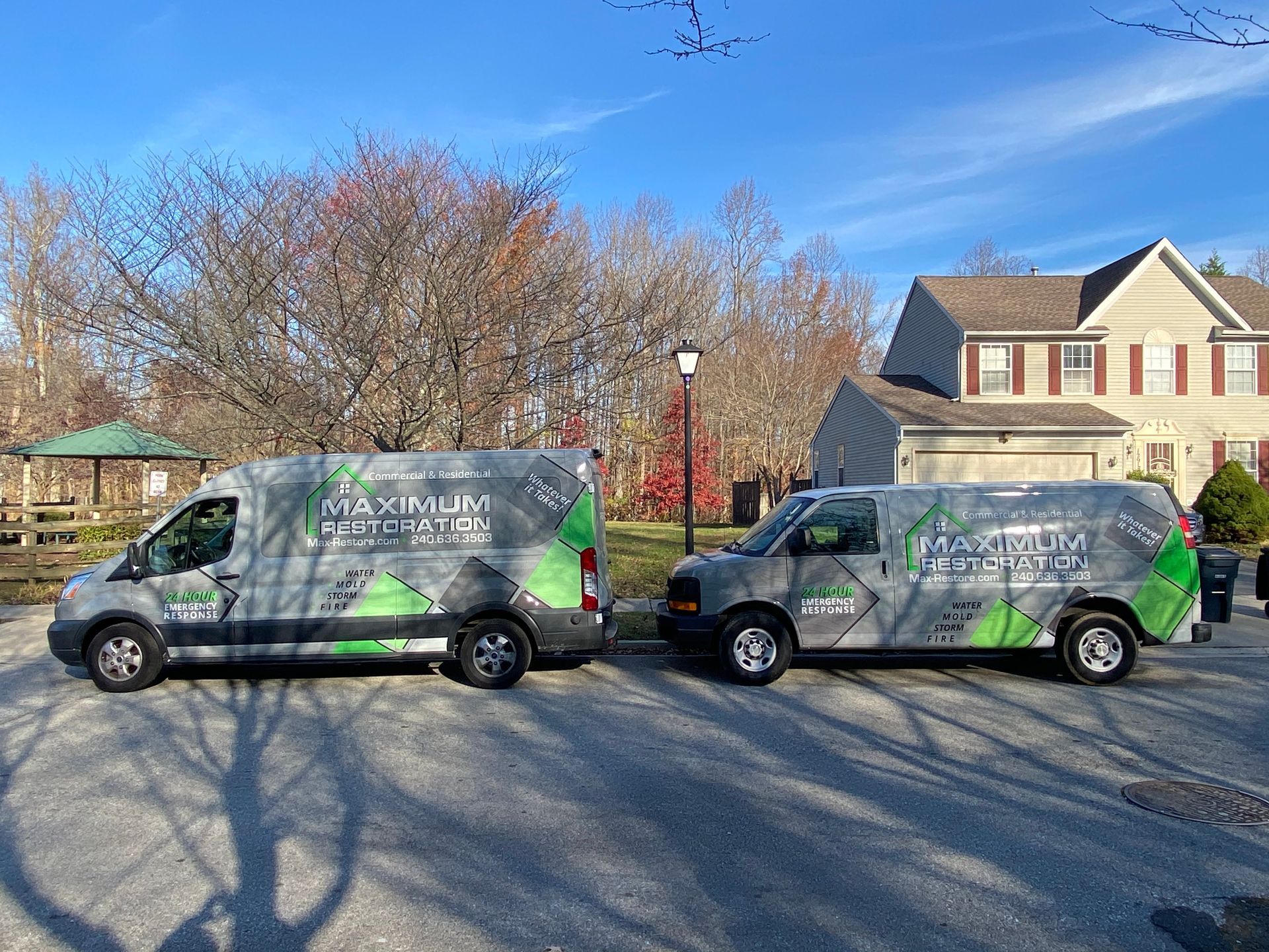 Two work vans parked on a residential street; both branded with 