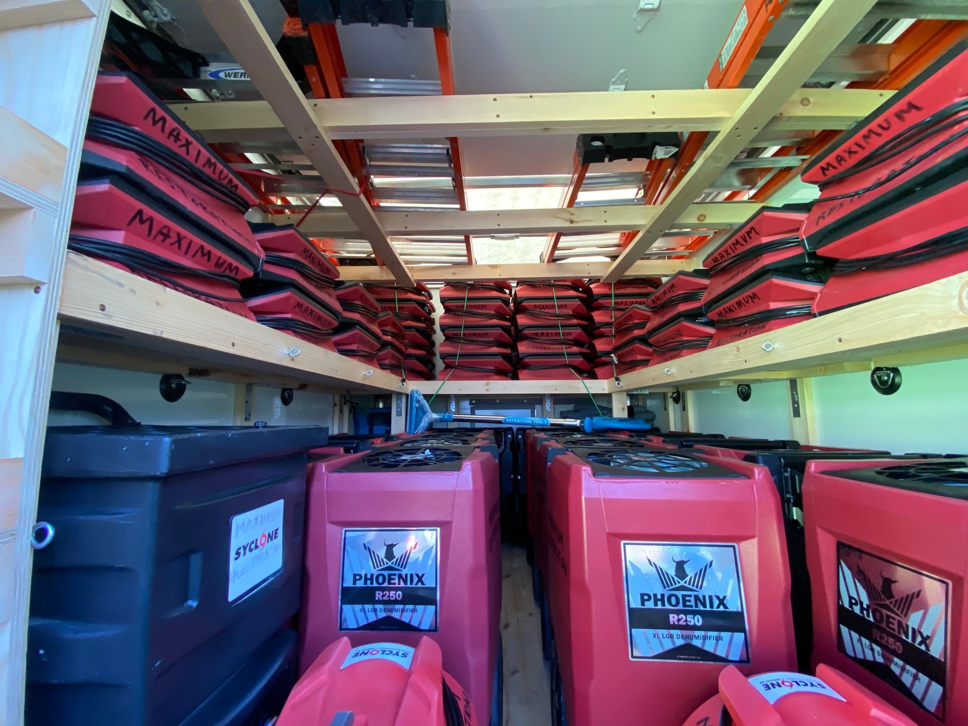 Inside a work van: red and black equipment on shelves, and large red units below.