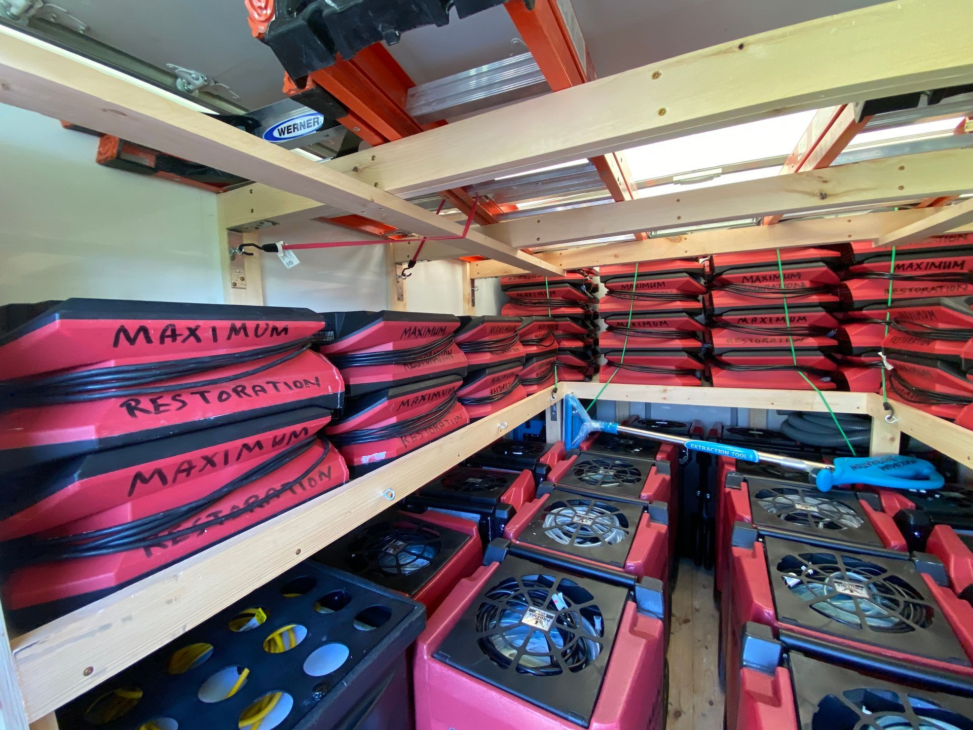 Storage unit filled with red and black restoration equipment and supplies, organized on shelves.