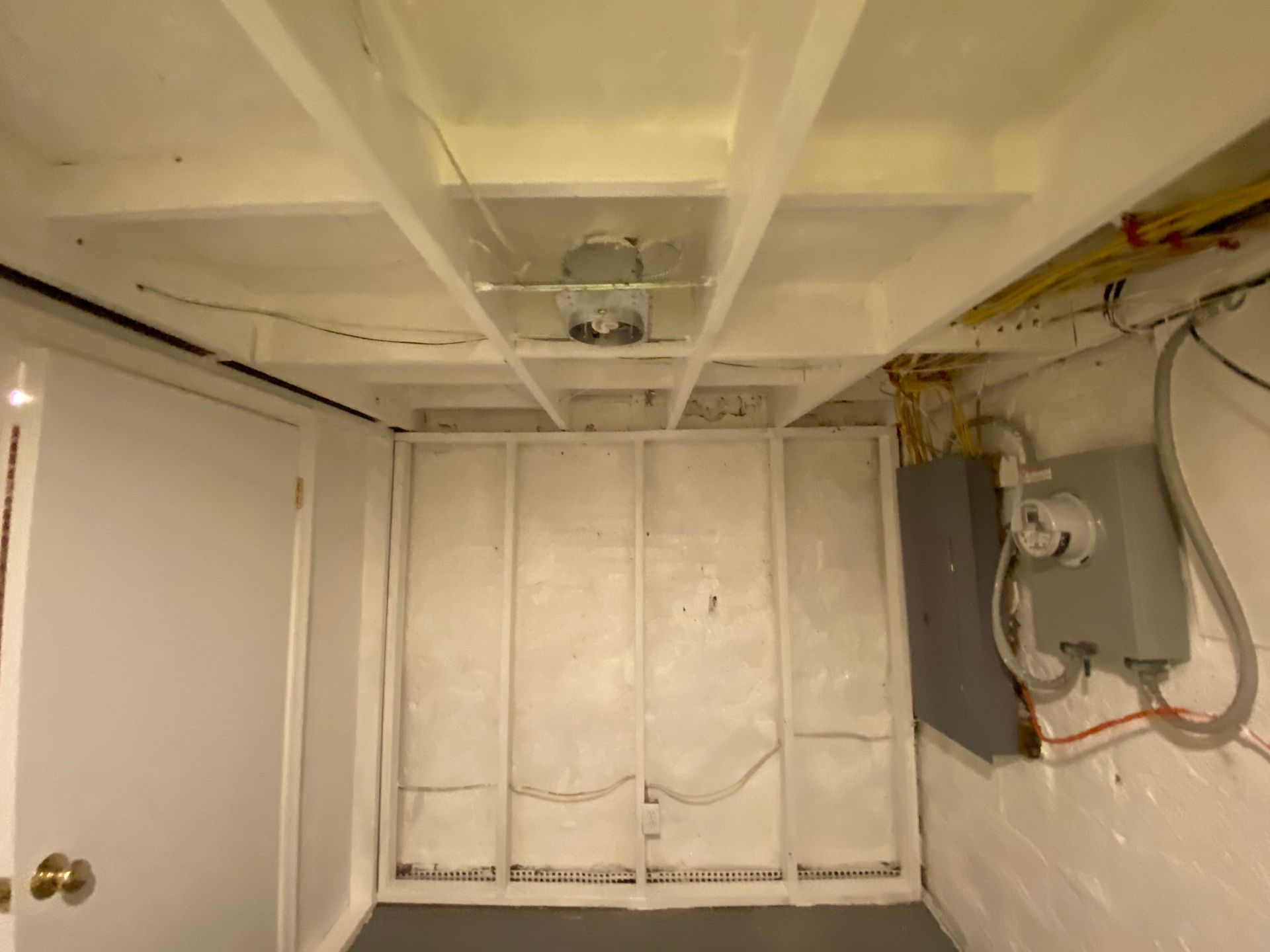 Basement ceiling with exposed beams, drywall, electrical, and a door.