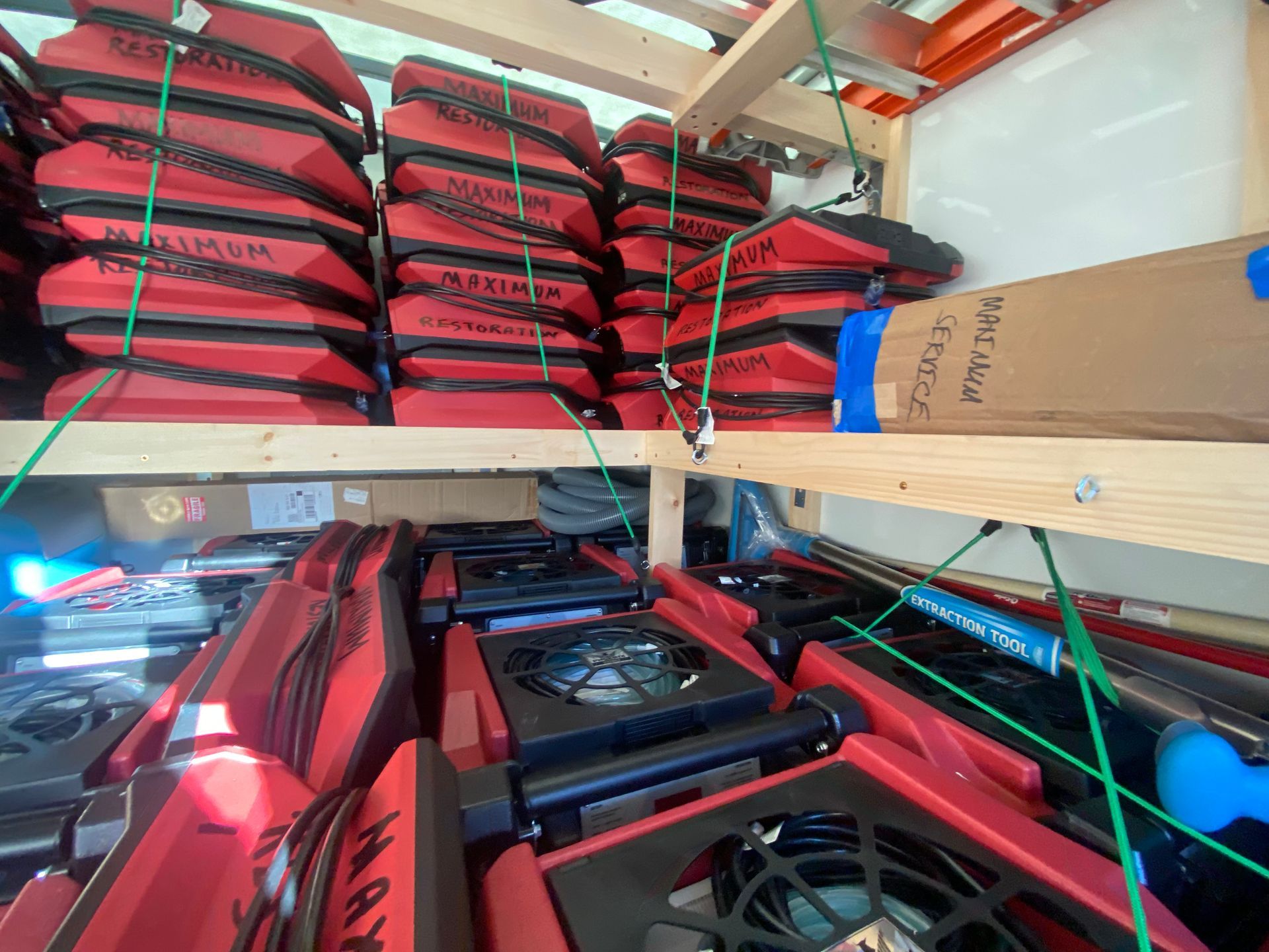 Shelves stacked with red kayak seats and life jackets, secured by green rope.