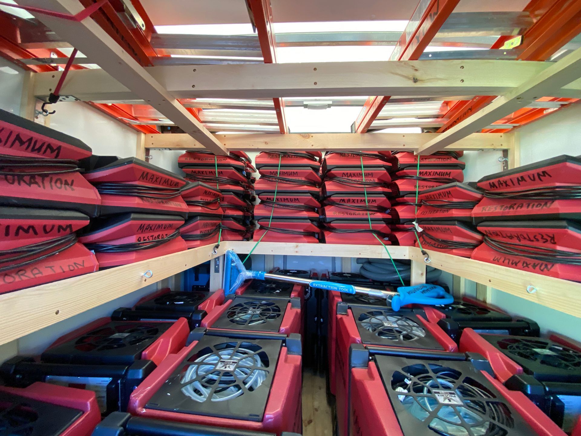 Interior of a truck filled with rows of red air movers and stacked red boxes, possibly containing more equipment.