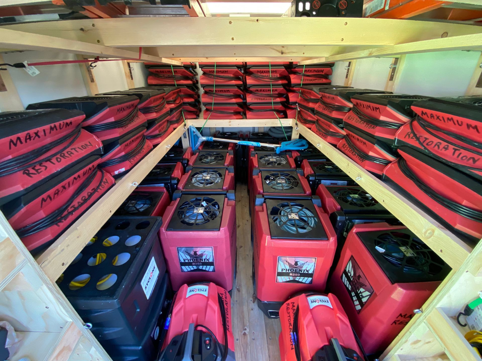 Interior view of a vehicle filled with rows of red and black equipment, likely for water damage restoration.