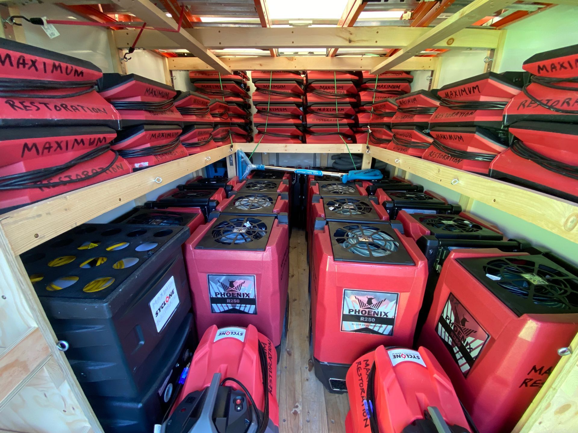 Interior of a trailer packed with red and black equipment, possibly for water damage restoration.