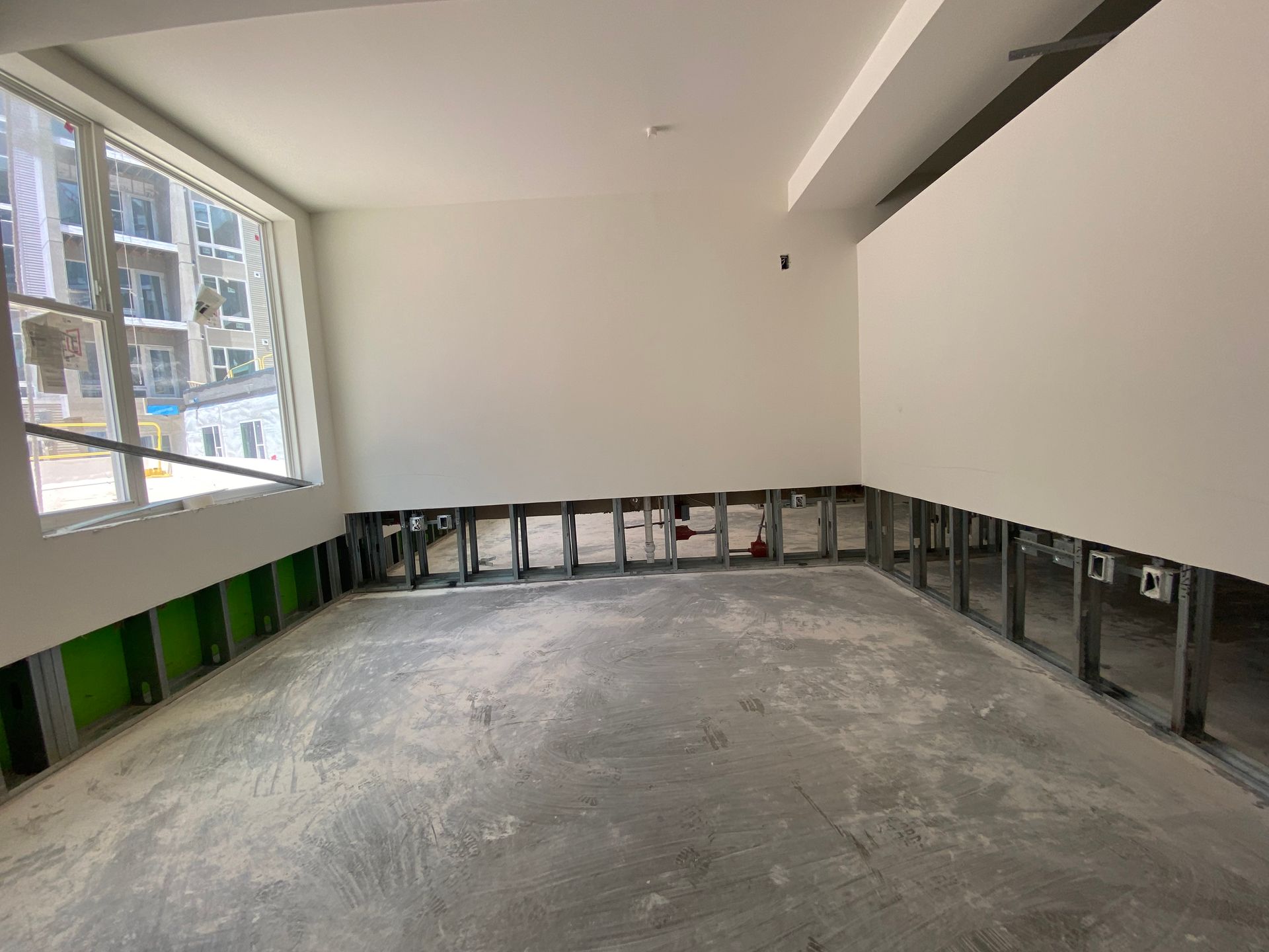 Interior construction site with exposed metal studs, unfinished walls, and concrete floor.