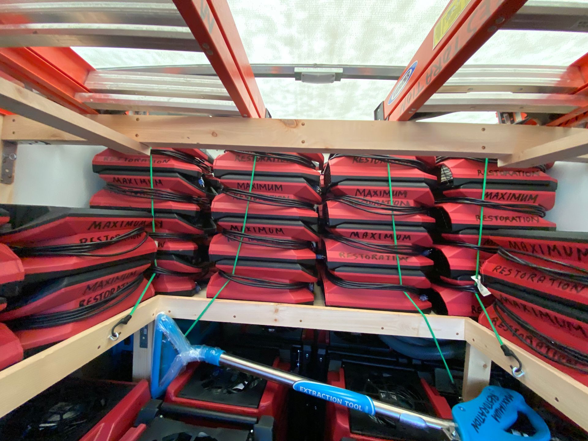 Red life vests stacked inside a wooden compartment, secured with green cords. A blue item rests below.