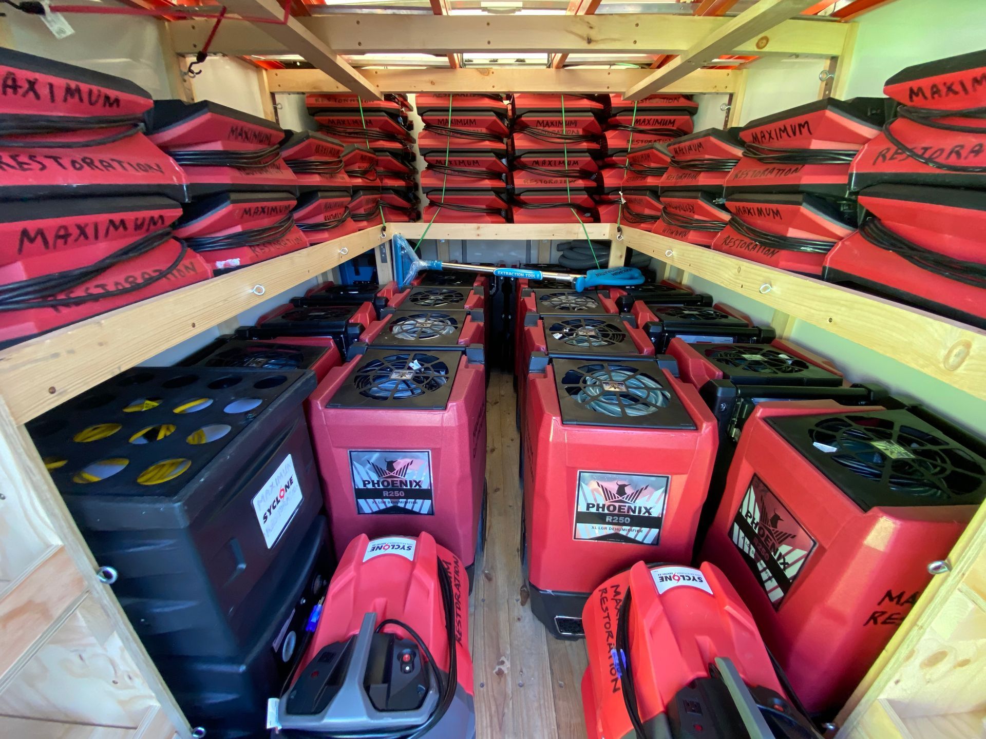 Interior of a truck filled with red, black, and gray equipment, including dehumidifiers and packaged materials labeled 