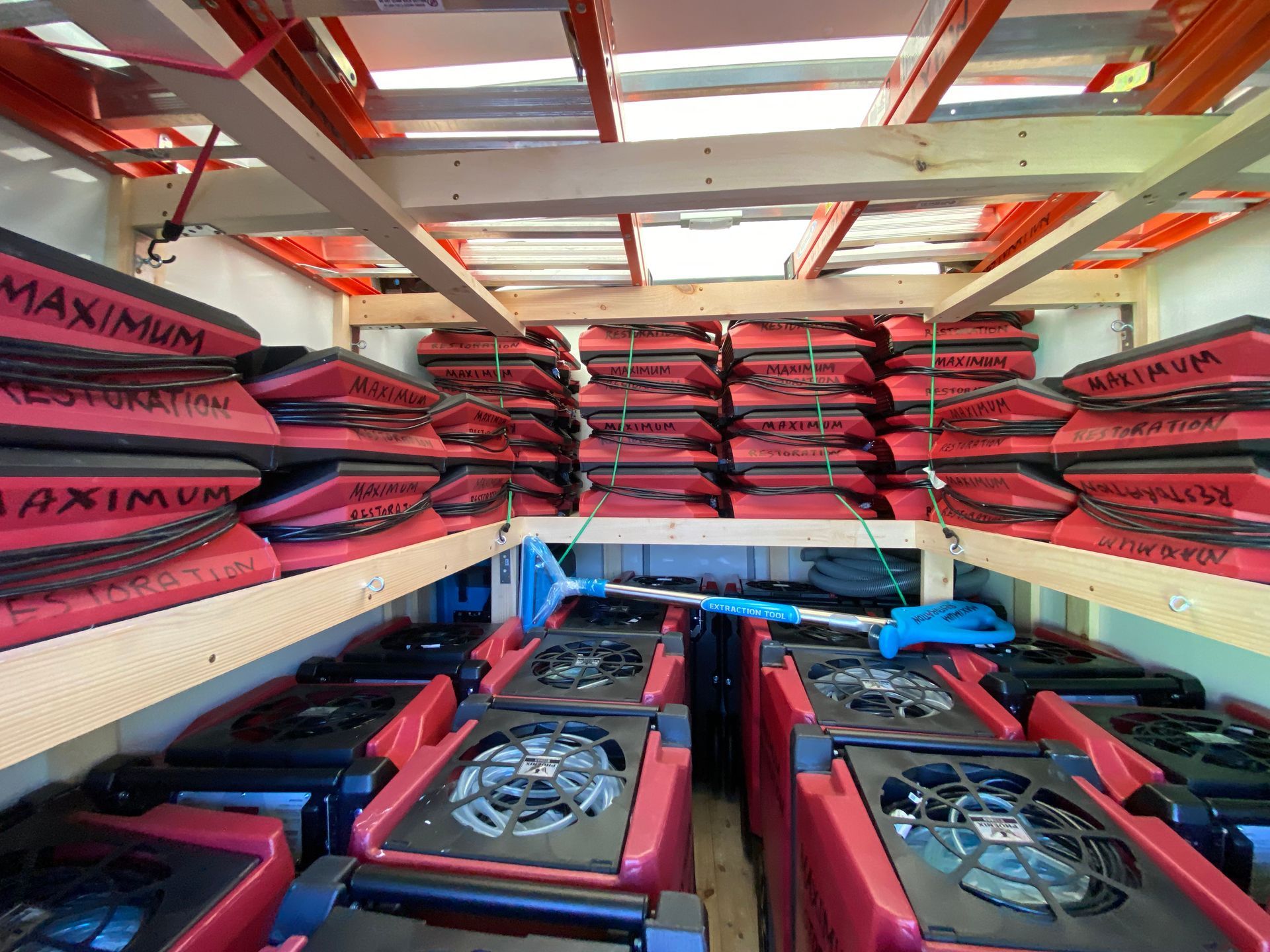 Interior view of a vehicle filled with stacked red drying machines and restoration equipment.