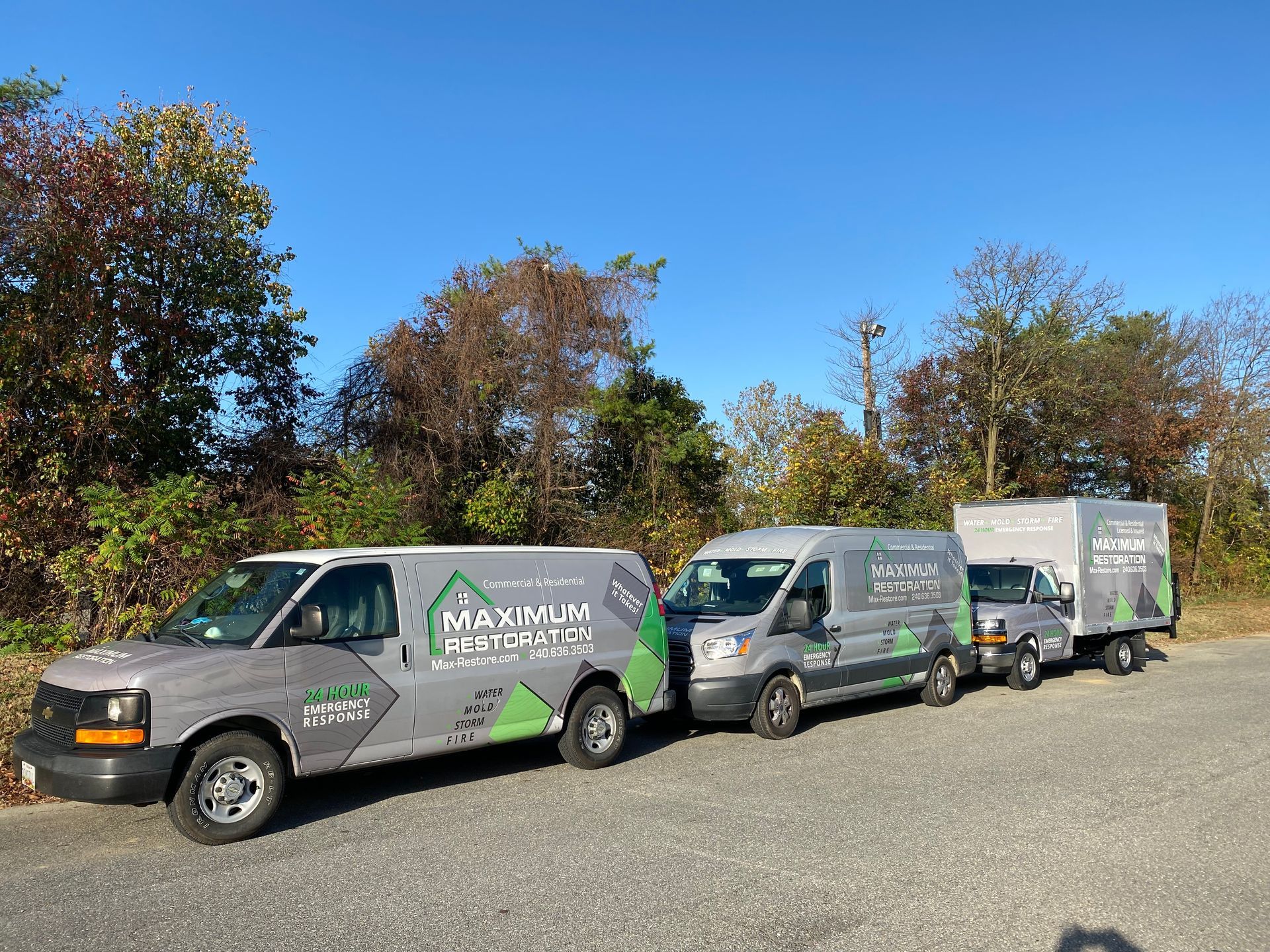 Three gray service vehicles parked outdoors on a sunny day.