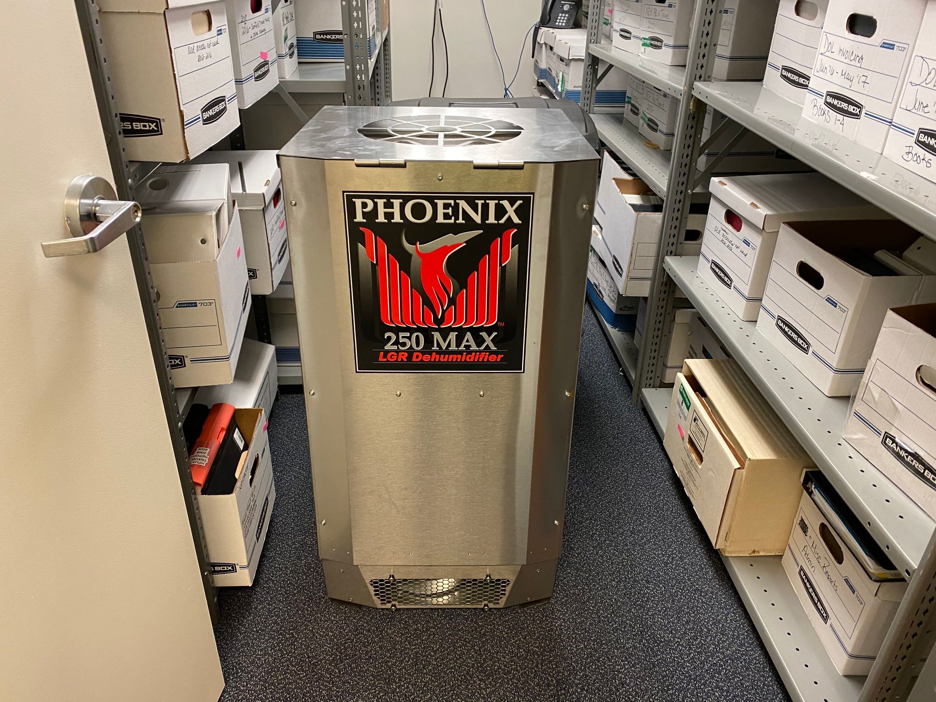 Phoenix 250 MAX dehumidifier in a storage room, surrounded by shelves of boxes.