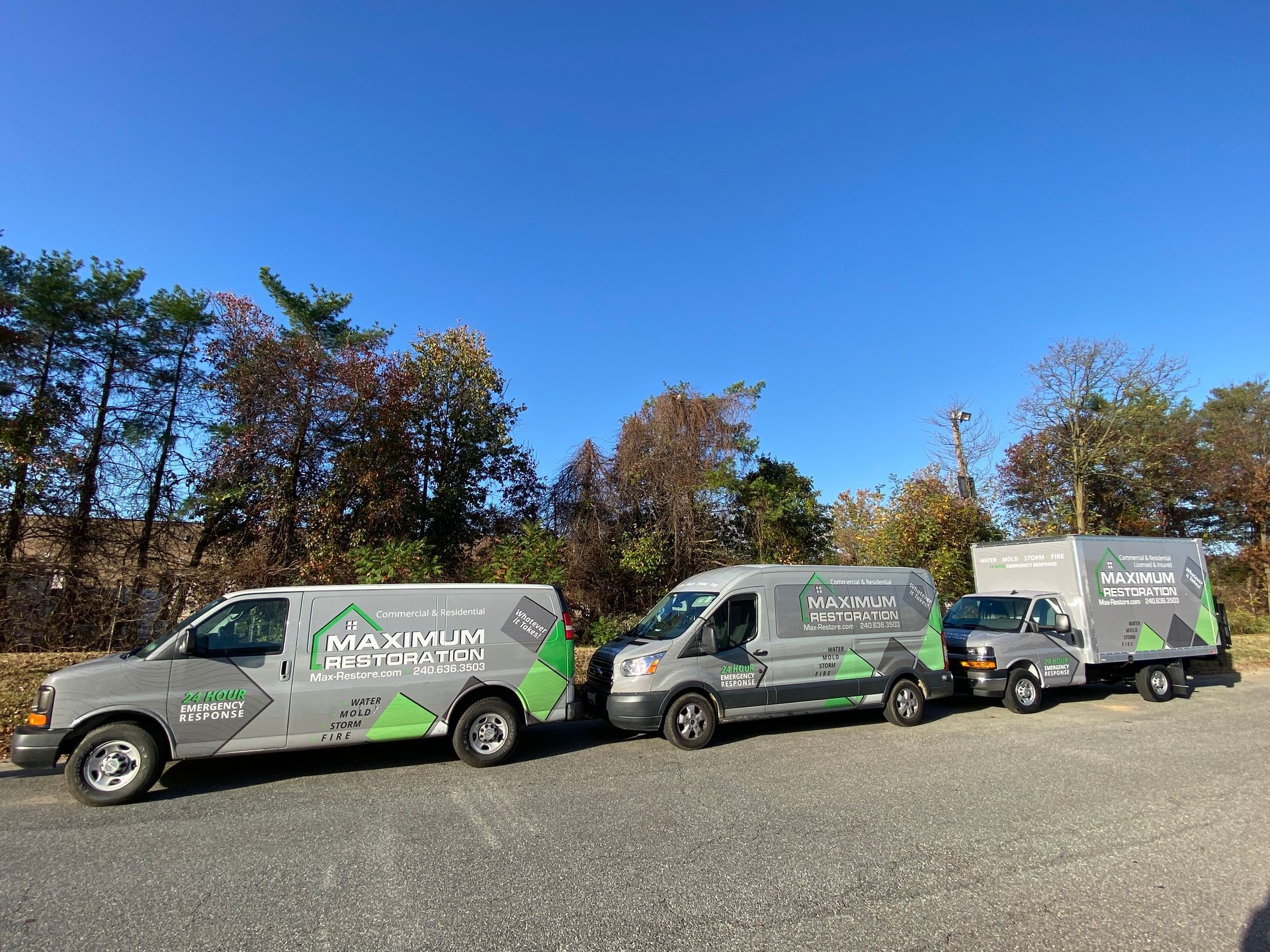Three gray service vehicles parked outdoors, each with the company name 