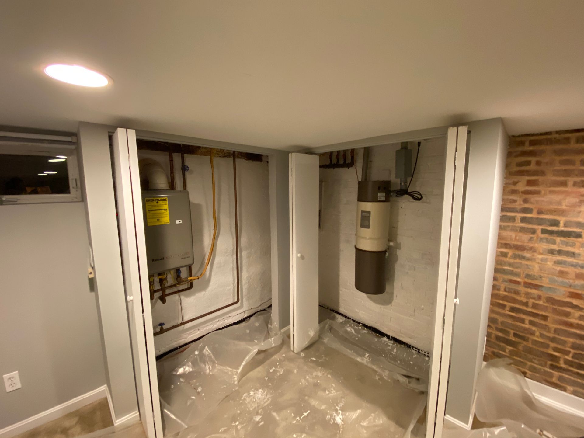Two utility closets in a basement with water heaters and exposed pipes.