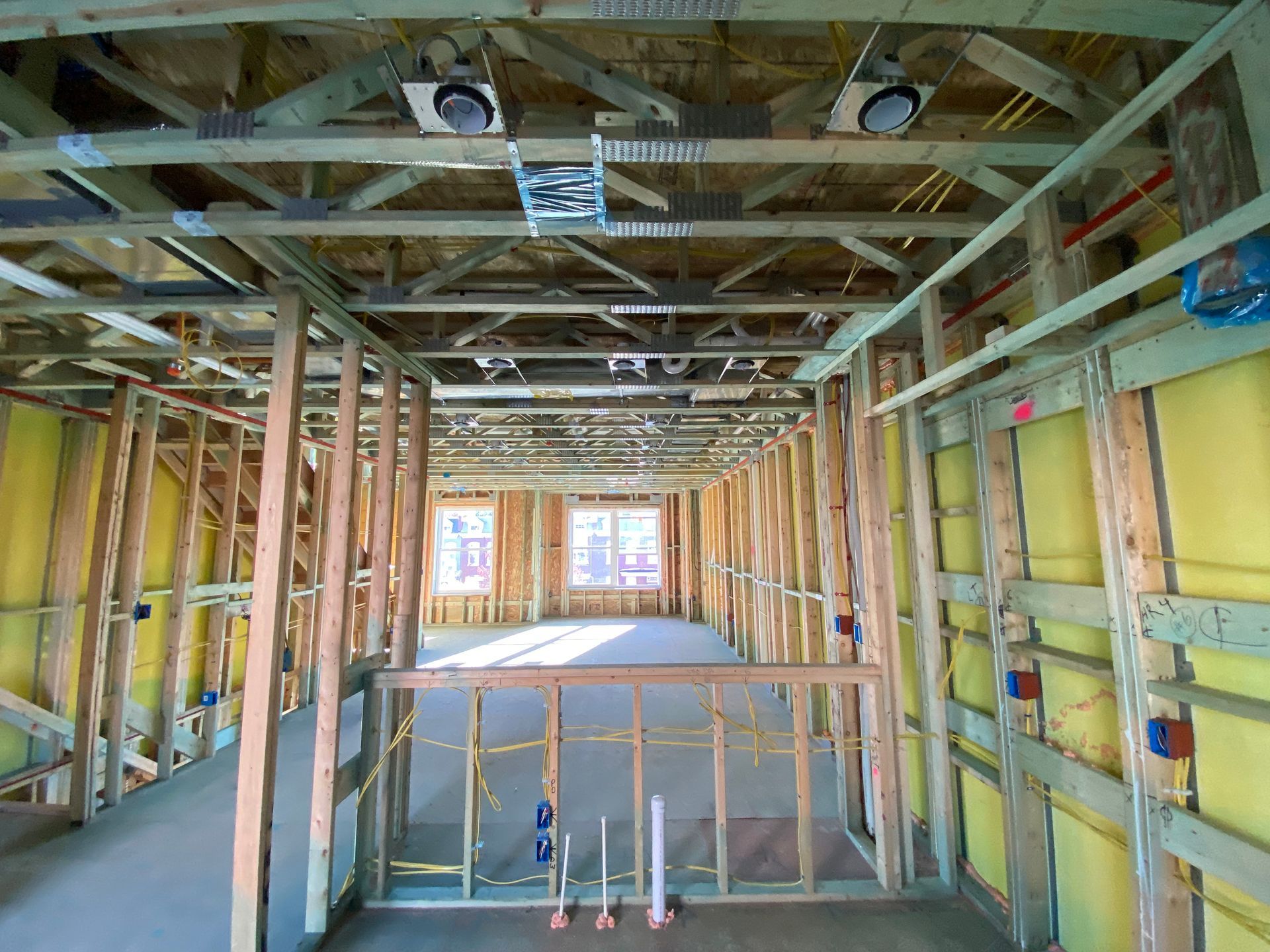 Interior view of a building under construction, showing wooden framework, insulation, and wiring.