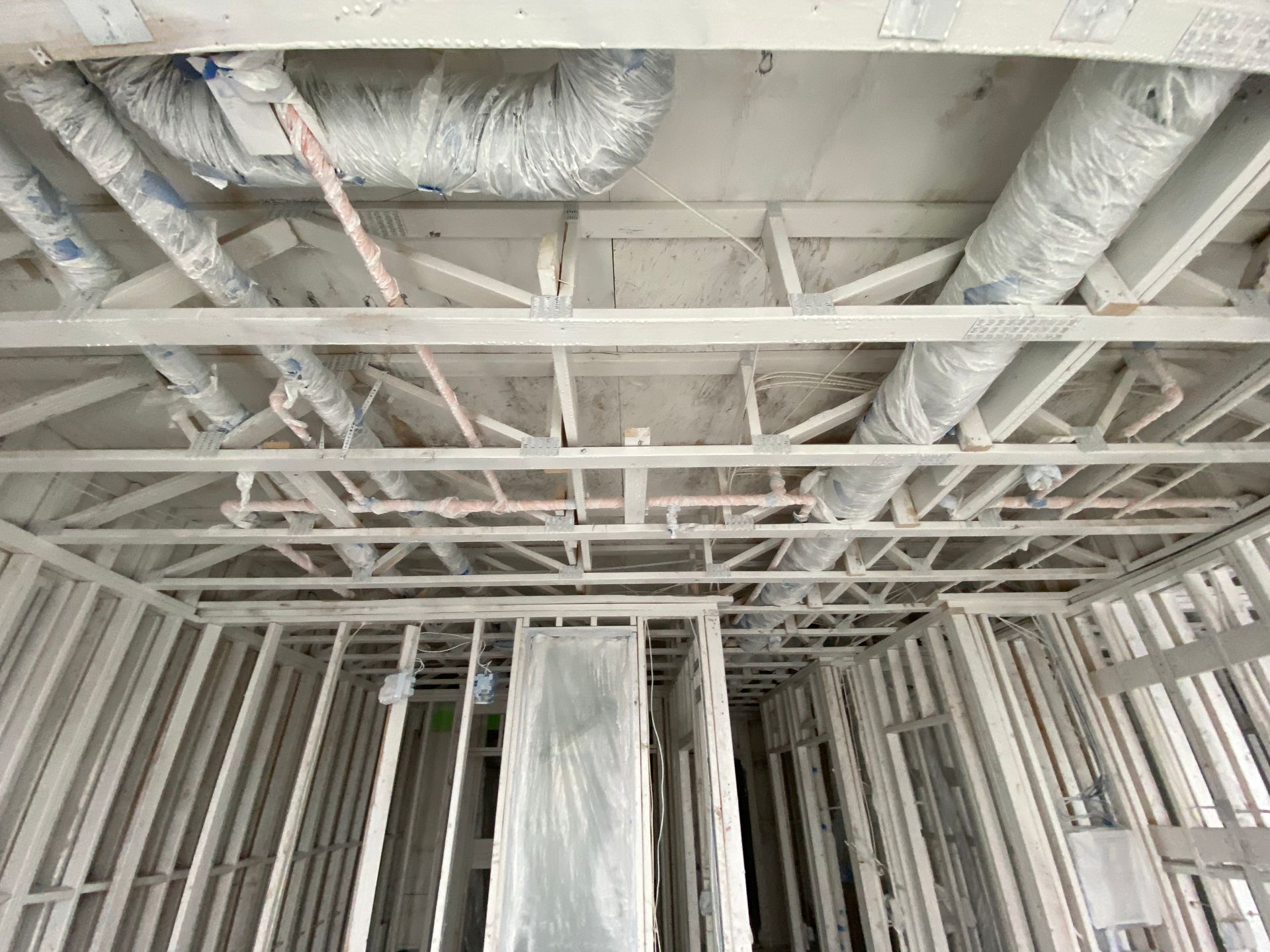 Interior view of a room under construction with exposed wooden beams, ductwork, and framing.