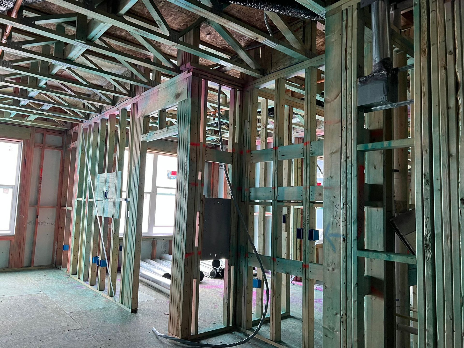 Interior of a building under construction, wooden framing visible; electrical boxes and wiring.