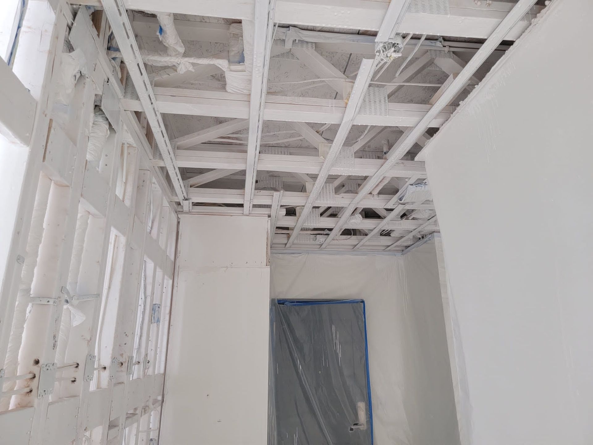 Construction site interior; exposed ceiling beams and wall studs painted white.