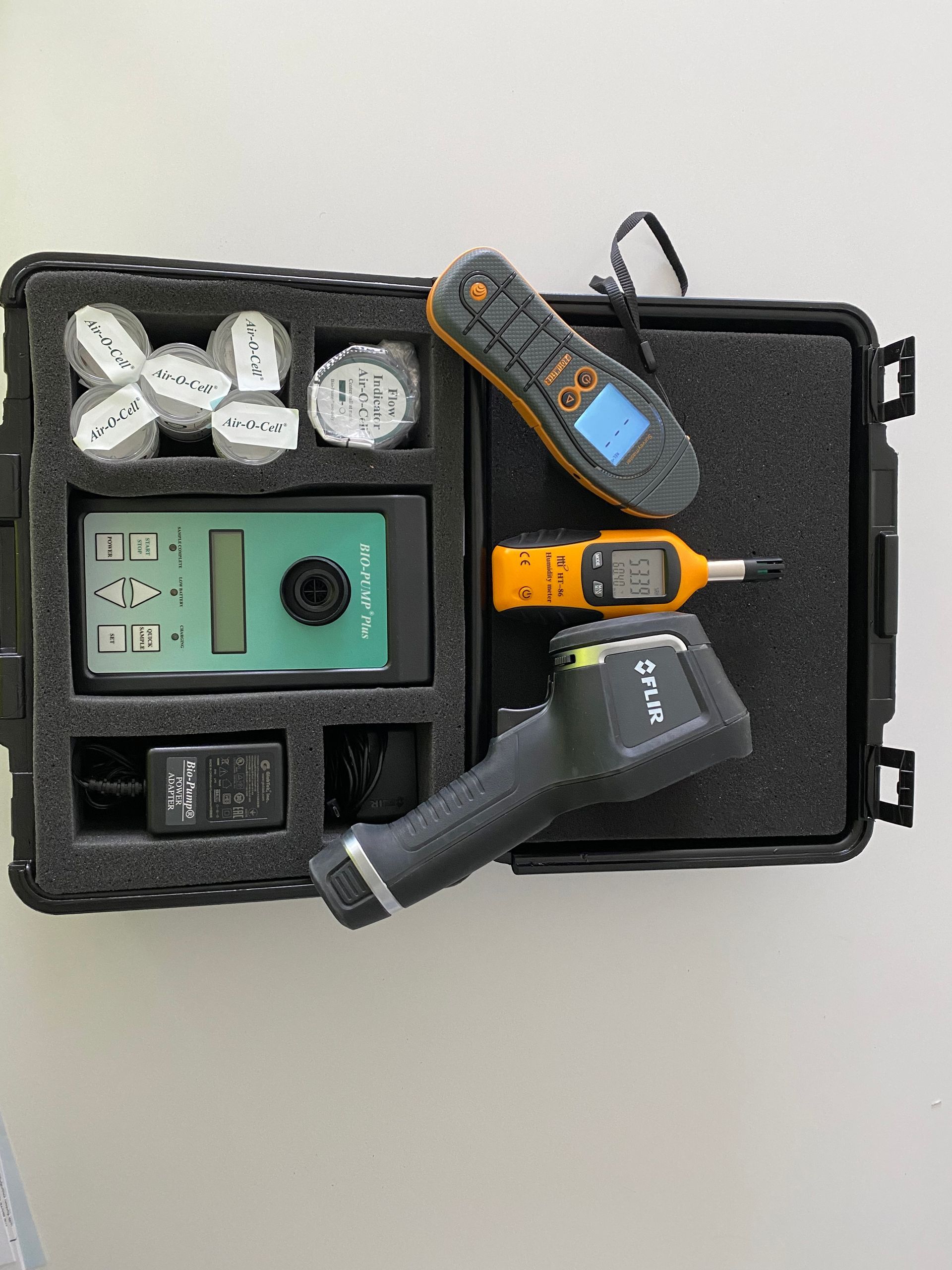A carrying case containing professional measurement tools, including an infrared thermometer, sensors, and a digital meter.