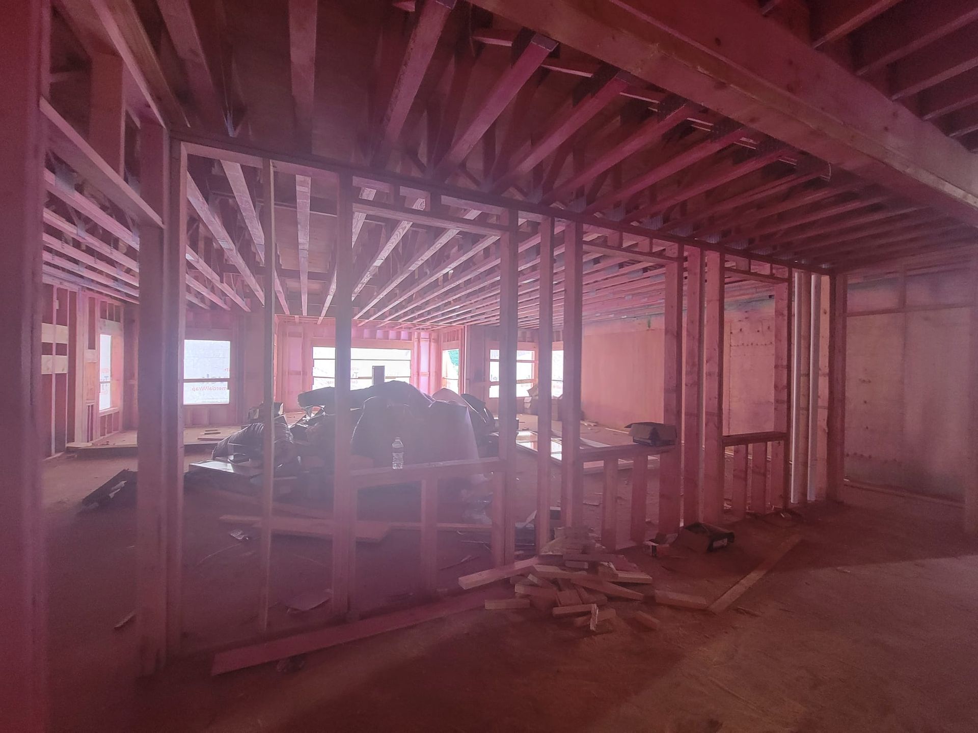 Interior view of a residential construction site featuring exposed wood wall framing and ceiling joists.