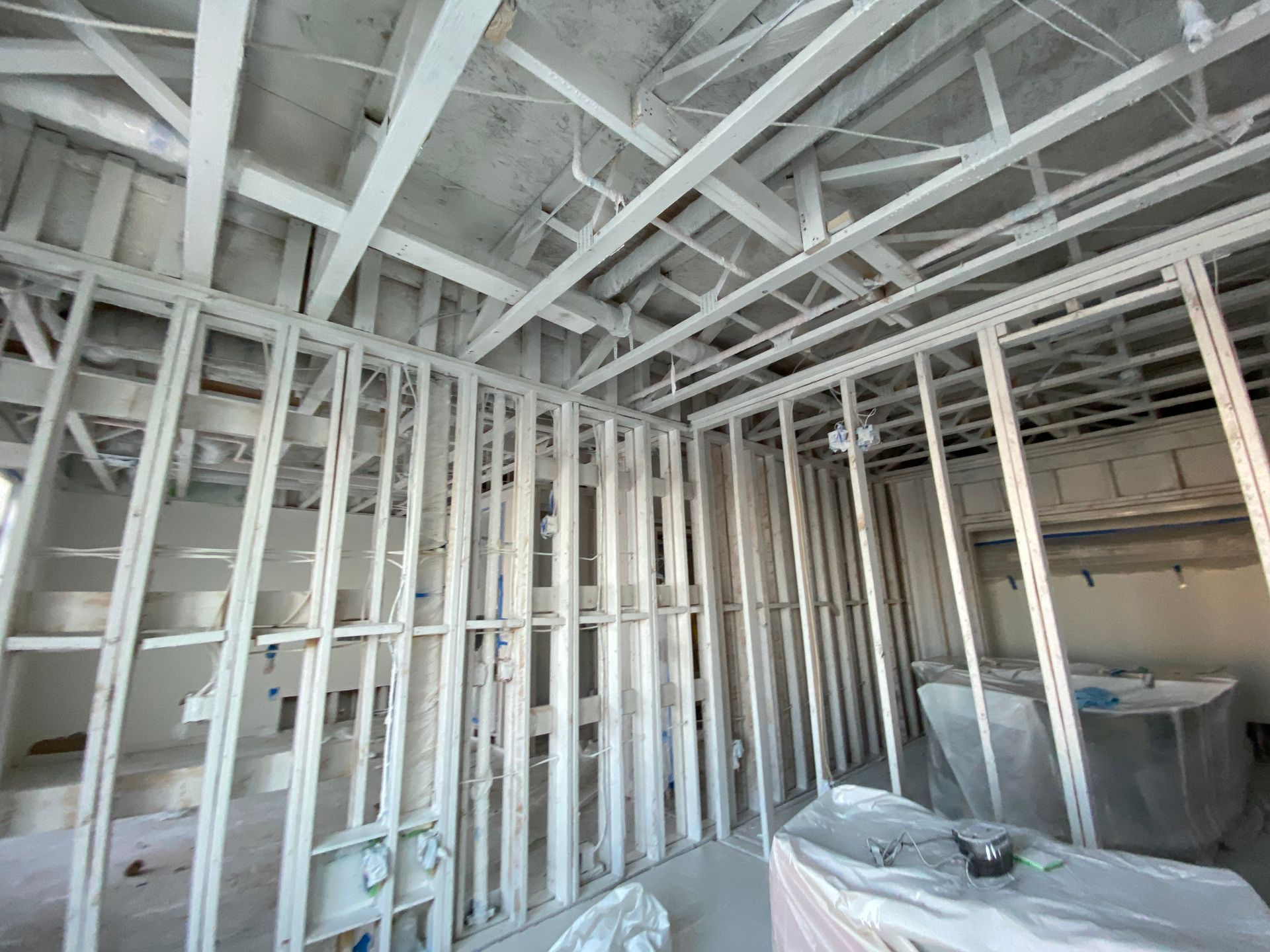 A room under construction featuring metal stud framing for walls and ceilings, with exposed concrete overhead.