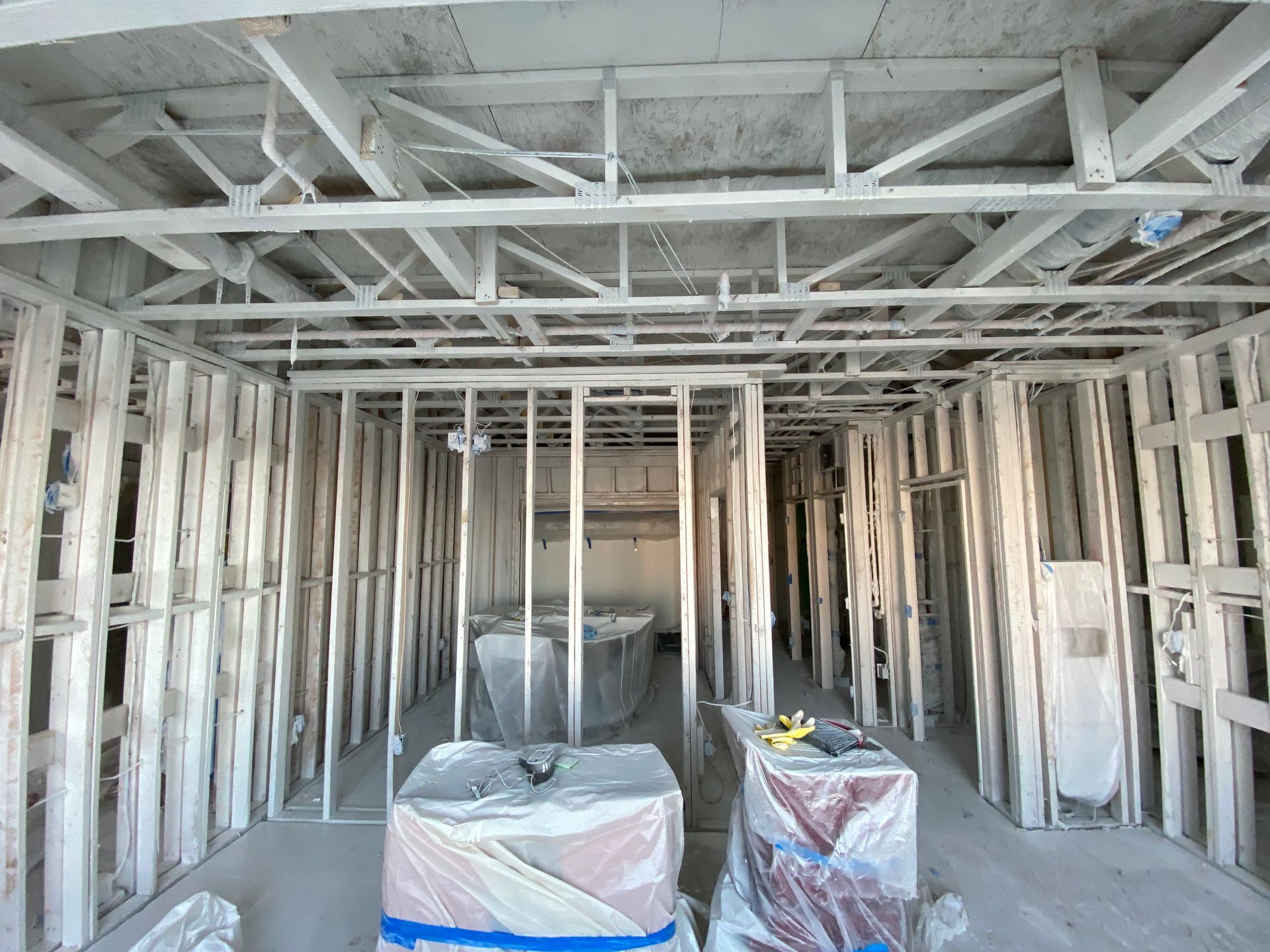 An interior room under construction featuring unfinished light-gauge metal wall studs and ceiling framing.