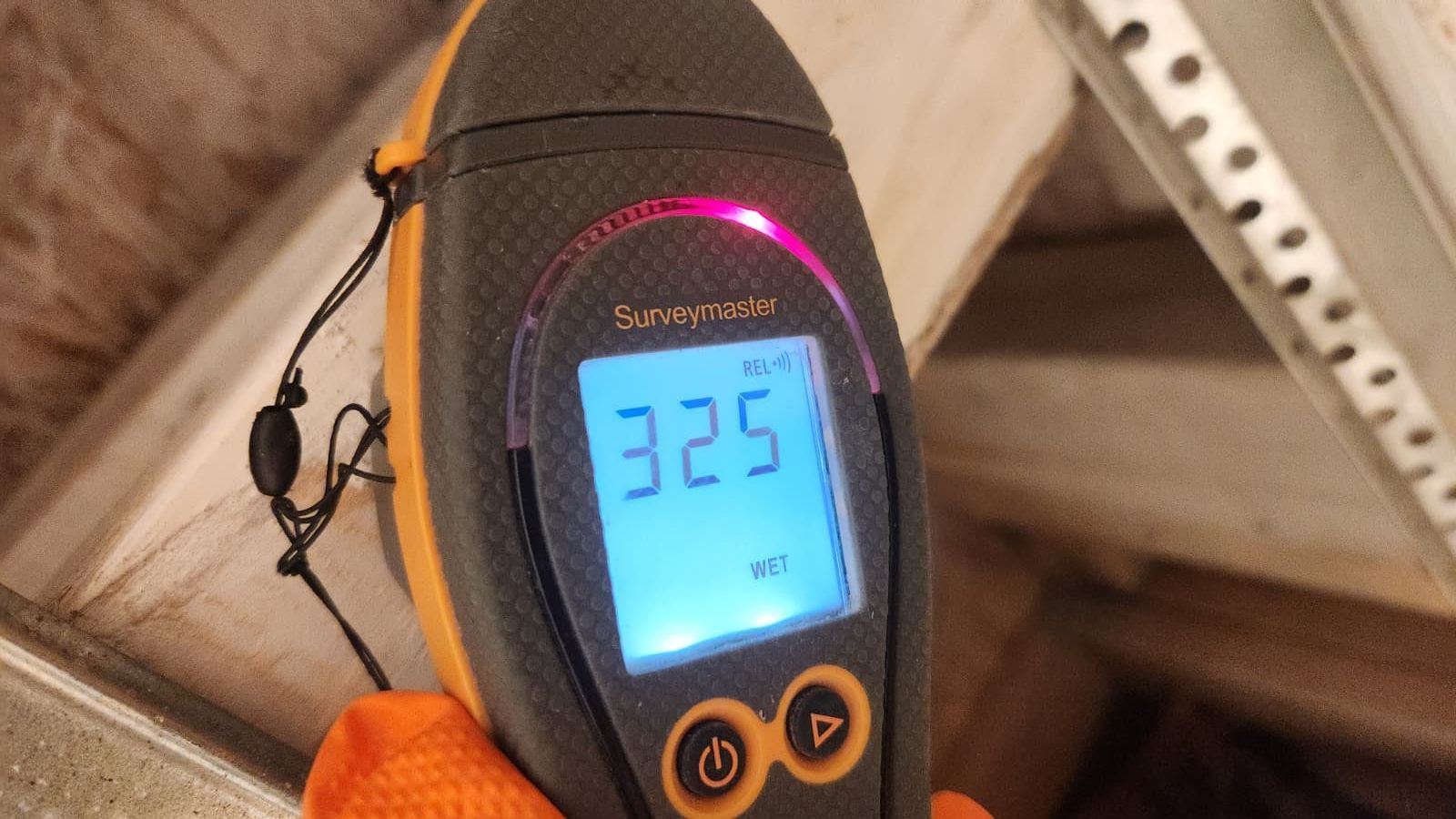 A hand wearing an orange glove holds a digital tire pressure gauge showing a reading of 32.5 PSI.