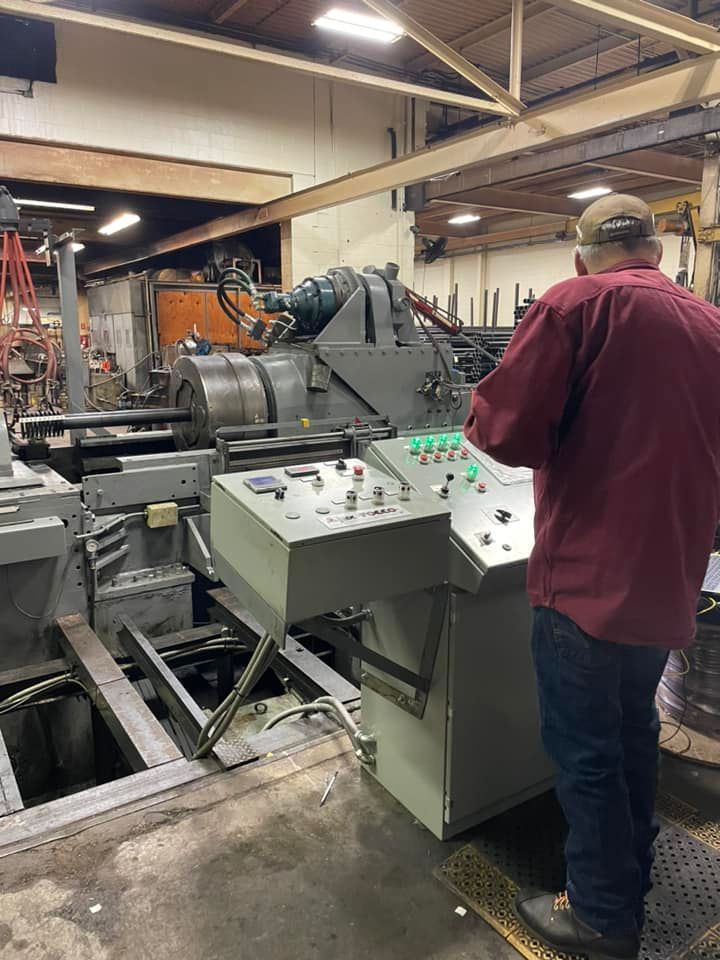 Worker operating industrial machine in a factory, with control panel and metal equipment nearby