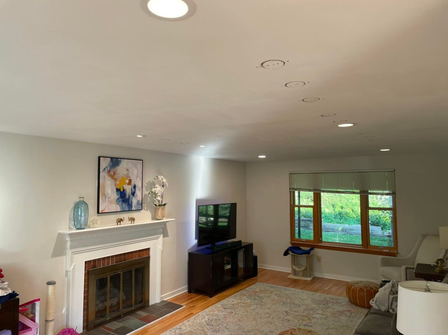 Living room with white fireplace, TV, window seat, and natural light on a rug